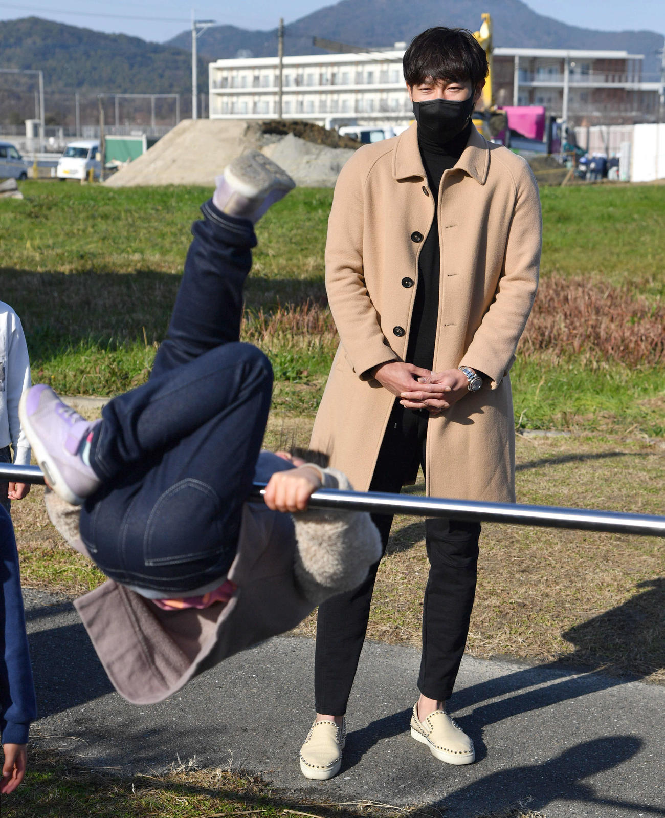 SOS子どもの村福岡を訪問し、鉄棒で遊ぶ子どもたちを見つめる柳田（撮影・岩下翔太）
