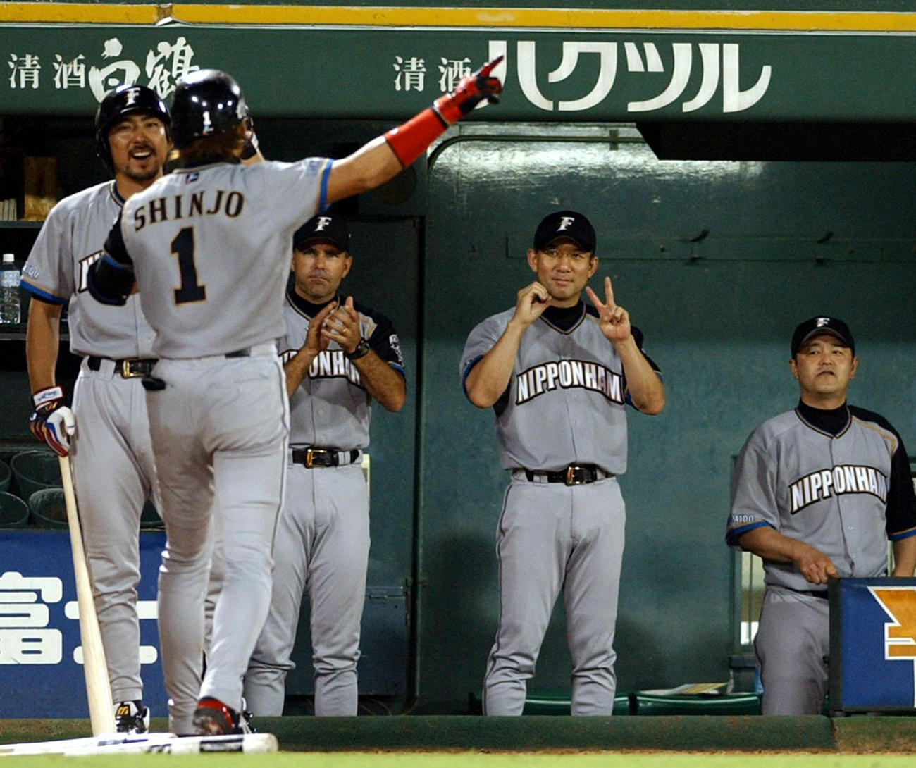 2004年9月6日、オリックス戦の5回に日本ハム新庄剛志は20号ソロを右中間へ放ち、ベンチ前で小笠原道大、トレイ・ヒルマン監督、白井一幸コーチ（右から2人目）、田村藤夫コーチ（右端）ら日本ハムナインに出迎えられる
