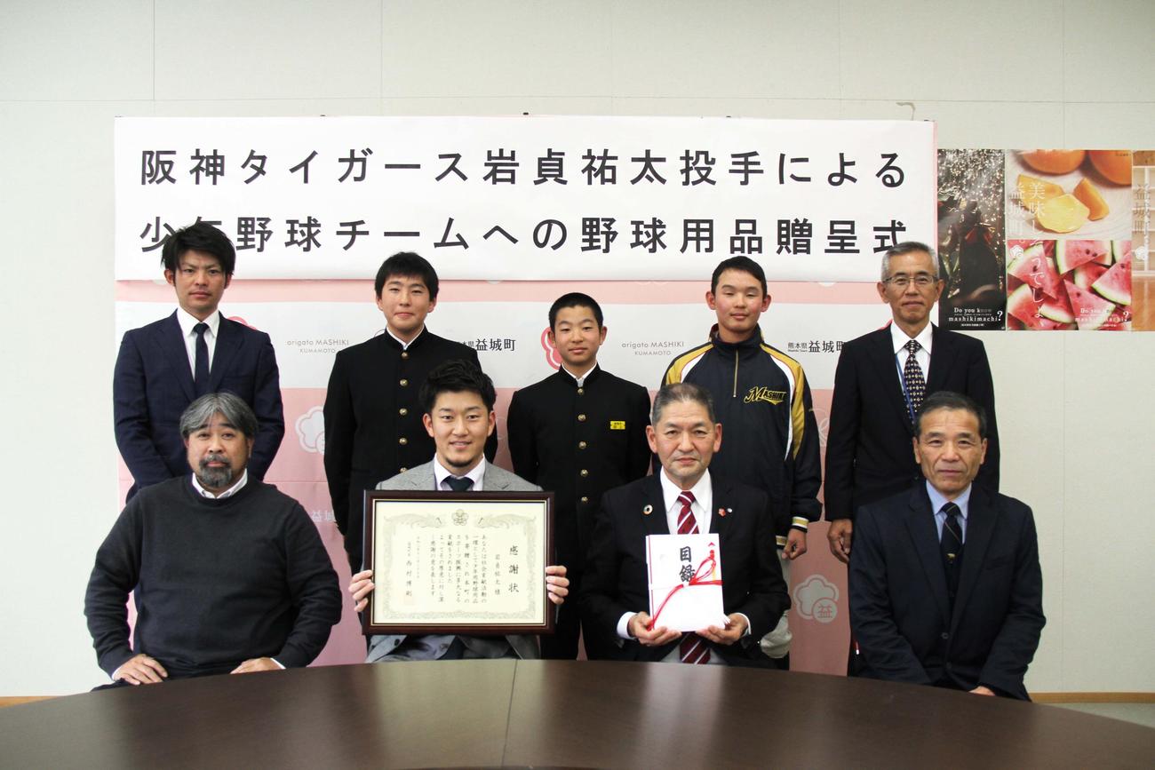 野球用品贈呈式で感謝状と目録を受け取り記念撮影する阪神岩貞（下段中央左）。同右は西村町長（益城町提供）