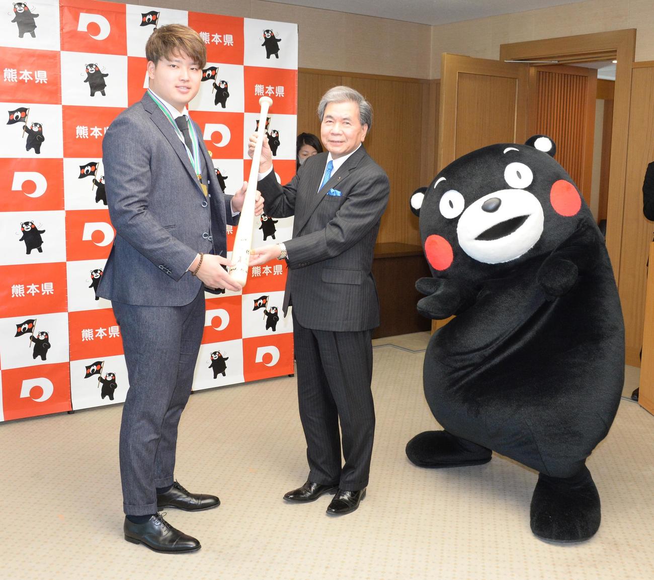 「くまもと夢づくり賞」を受賞したヤクルト村上は、蒲島知事（中央）の要望に応えてバットにサインする。右はくまもん（撮影・鈴木正章）