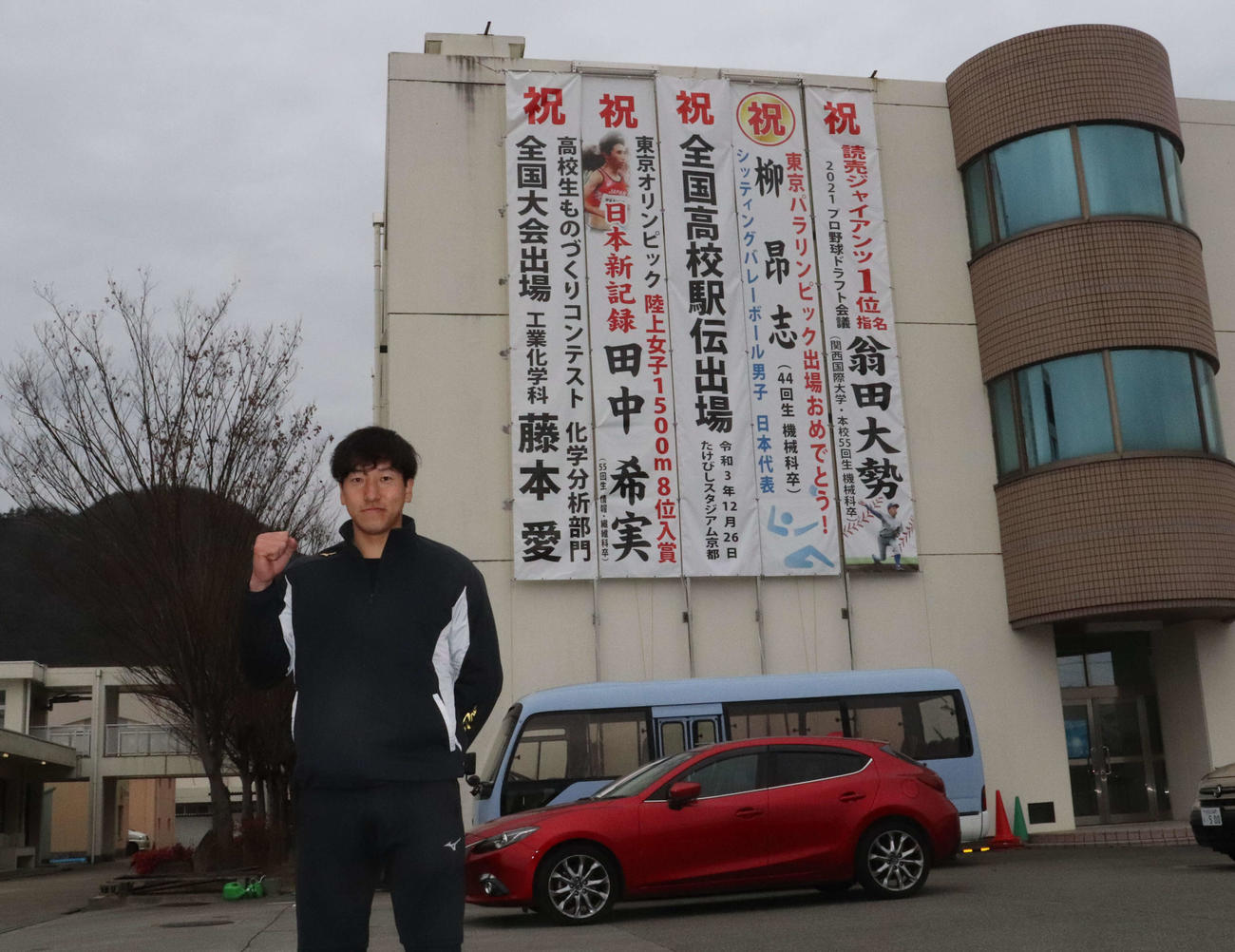 母校・西脇工にかけられた垂れ幕を背後に写真撮影に応じる巨人ドラフト1位の関西国際大・翁田（撮影・小早川宗一郎）