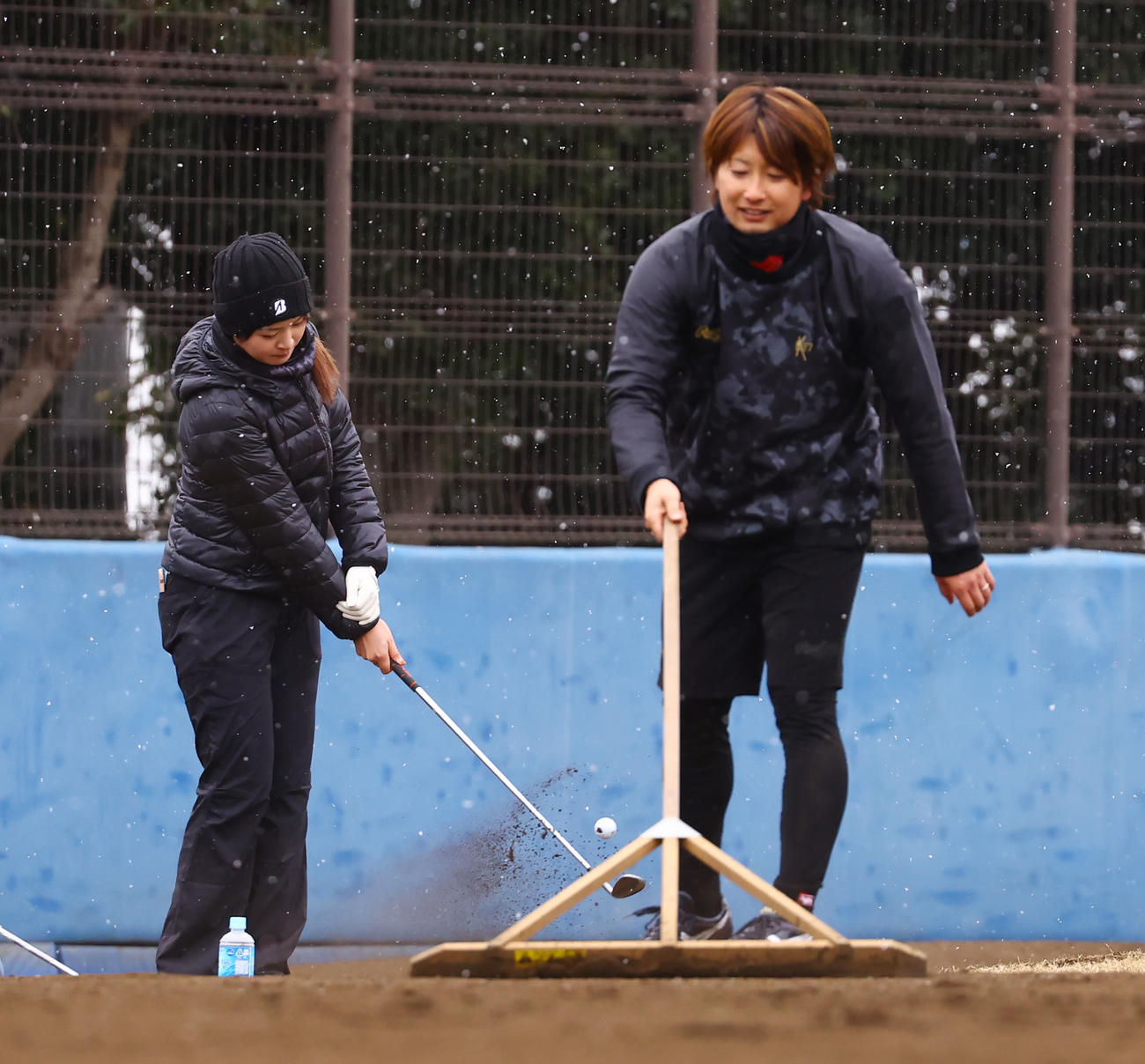 合同自主トレでノックを終えグラウンド整備する選手たちを横目にゴルフの練習を行う三ヶ島（左）（撮影・垰建太）