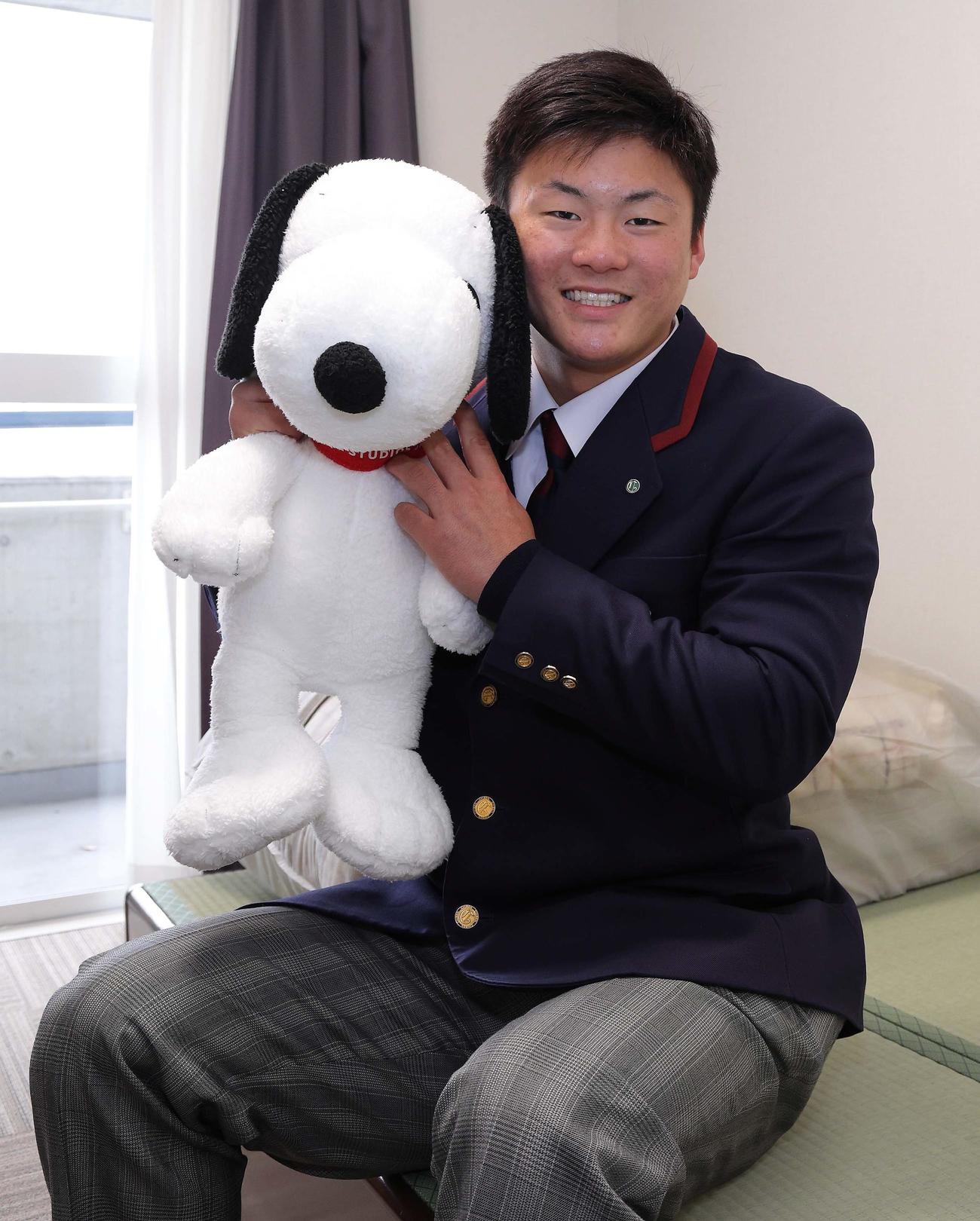 スヌーピーのぬいぐるみを手に笑顔を見せる阪神ドラフト4位の前川（球団提供）