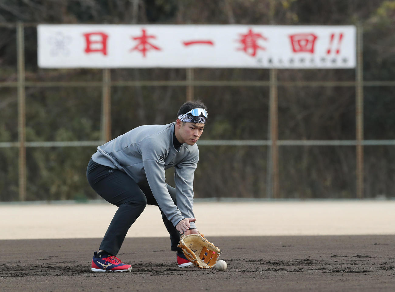 母校近大のグラウンドでの自主トレを公開し、「日本一奪回!!」の横断幕を背に三塁でノックを受ける阪神佐藤輝（撮影・前田充）