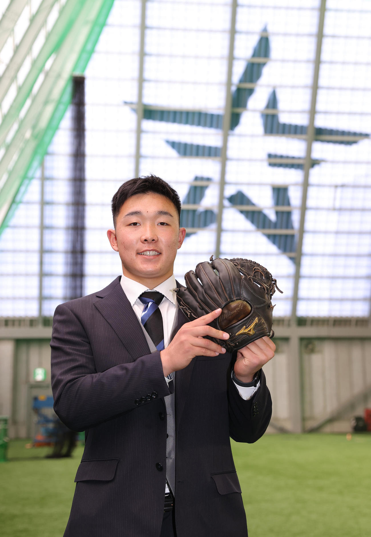 入寮を終えグラブを手に記念撮影に納まるDeNAドラフト3位の粟飯原（撮影・河野匠）