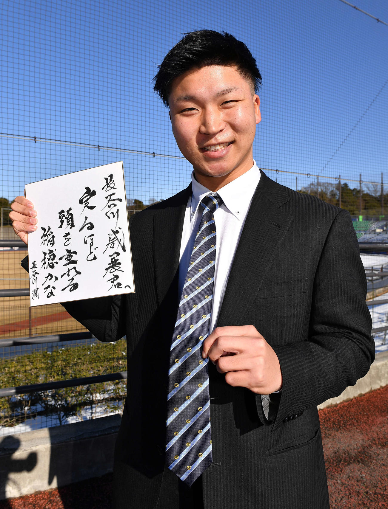 プレゼントされた色紙とネクタイを手に笑顔で入寮する日本ハムドラフト6位長谷川威展（2022年1月7日代表撮影）