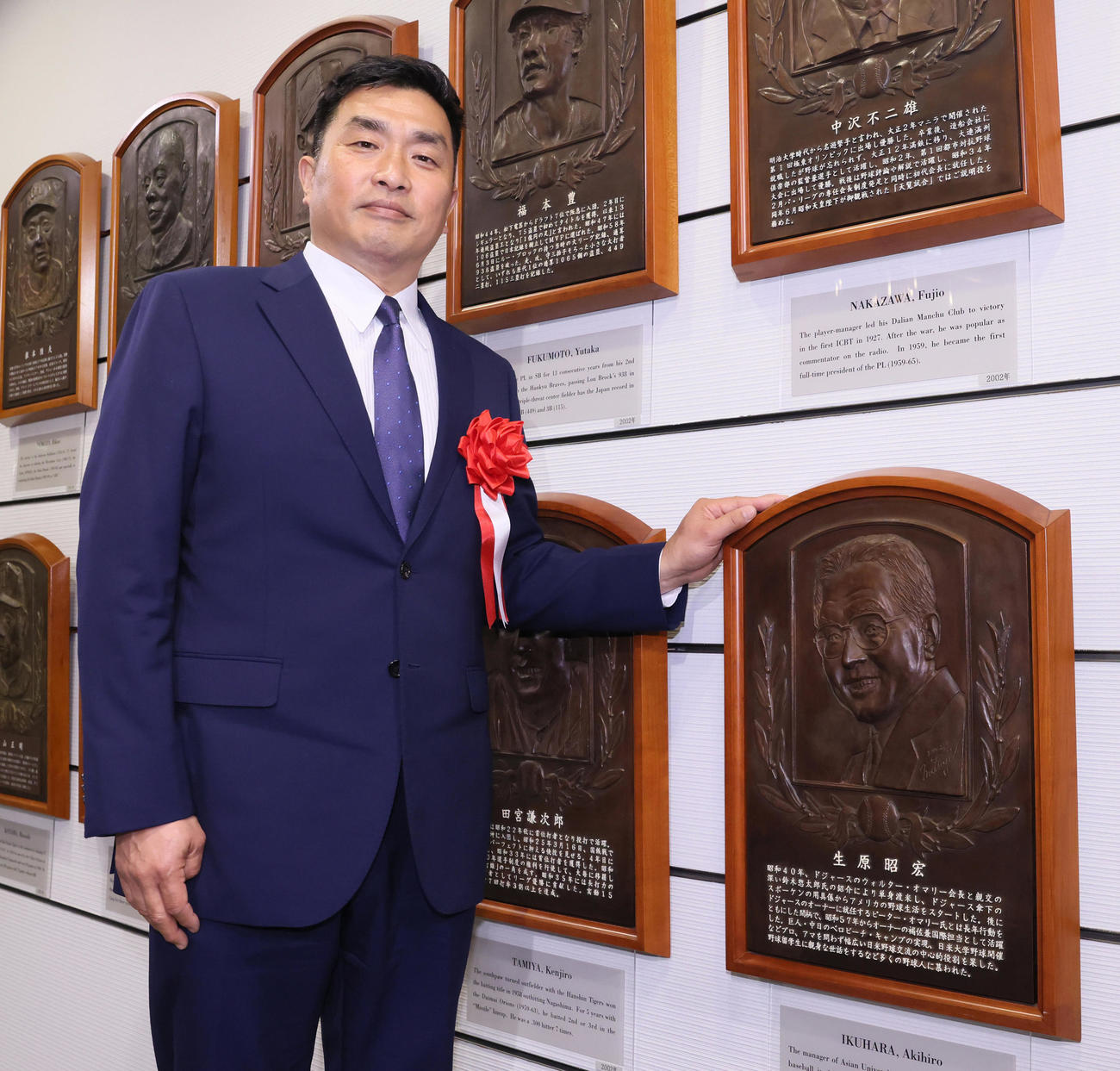 故アイク生原さんのレリーフと記念撮影する山本氏（代表撮影）