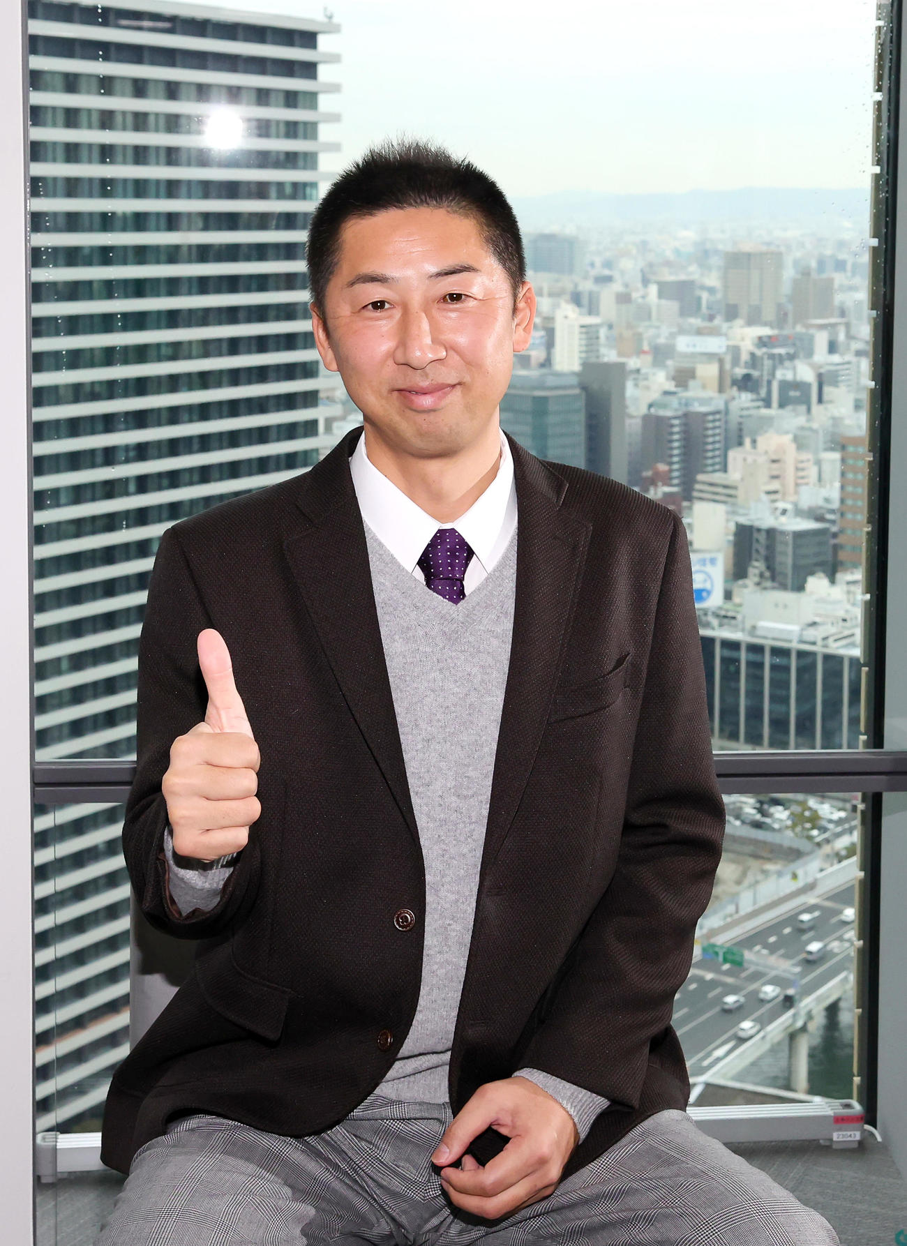 本紙評論家の仲間入りした今岡氏は大阪の街並みをバックにポーズを決める（撮影・上山淳一）