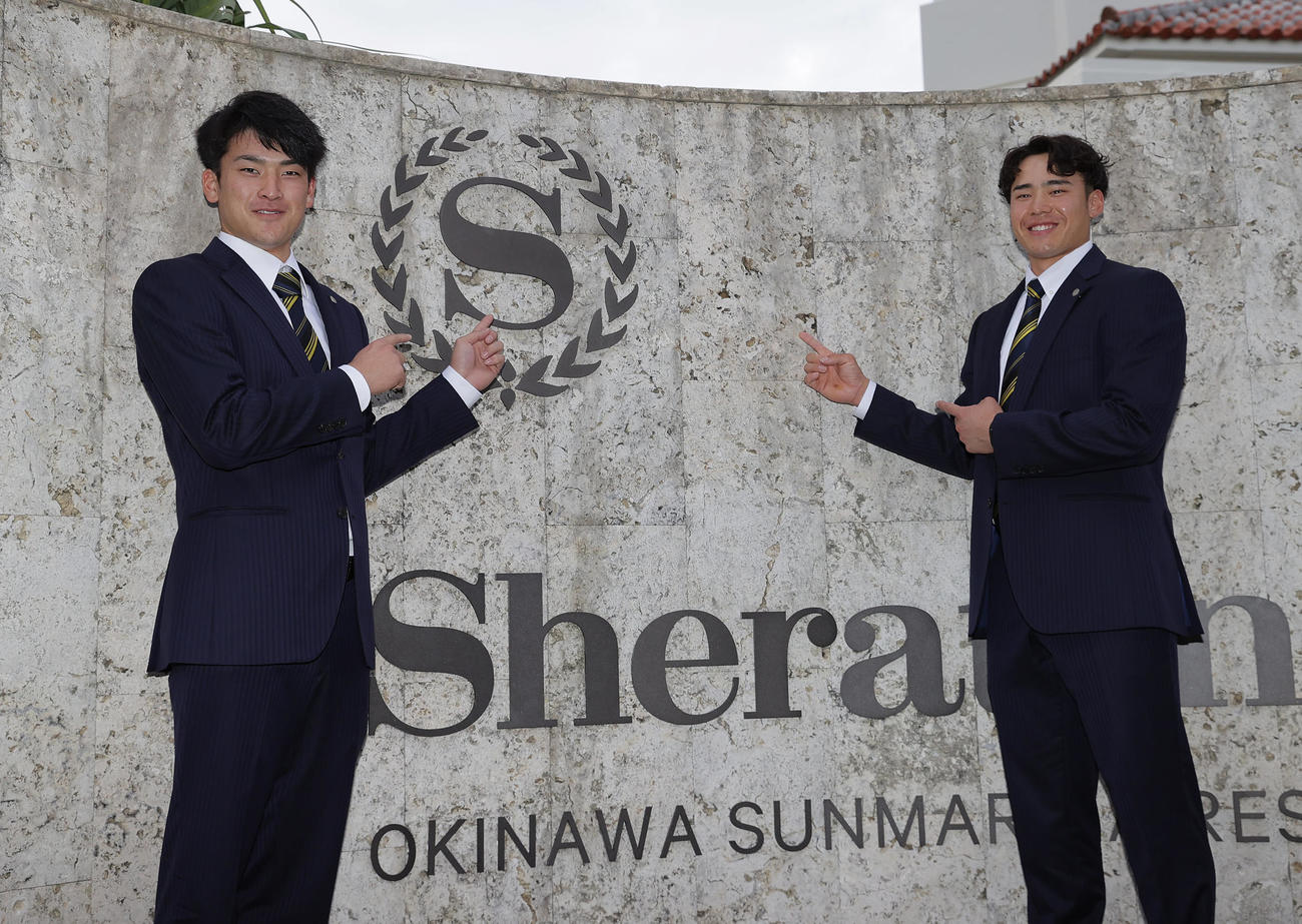 沖縄入りしてチーム宿舎に到着し、ホテルシェラトンのロゴを指さす阪神高寺（左）と遠藤（撮影・前田充）