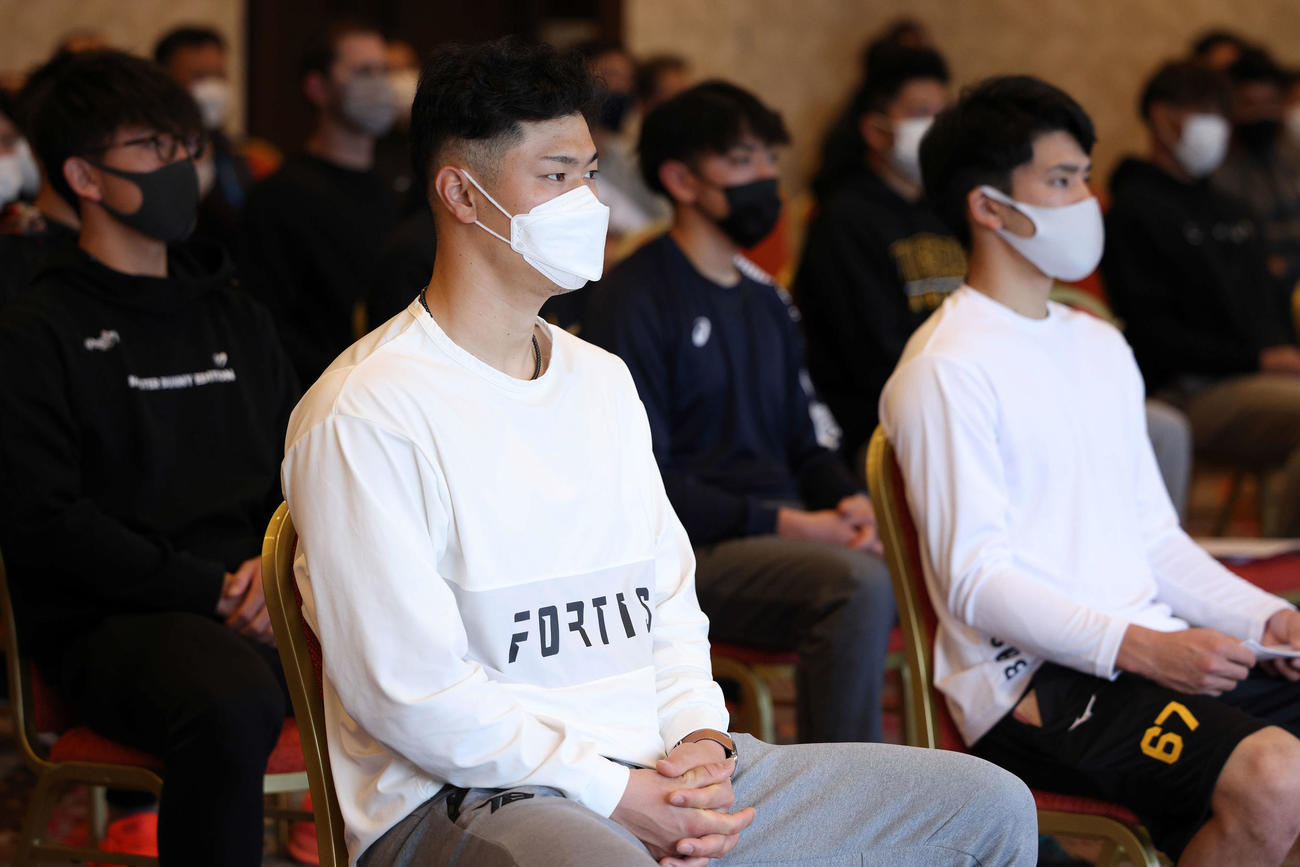 キャンプ前日ミーティングに出席し、神妙な面持ちで話を聞く阪神佐藤輝（中央）ら選手たち（球団提供）
