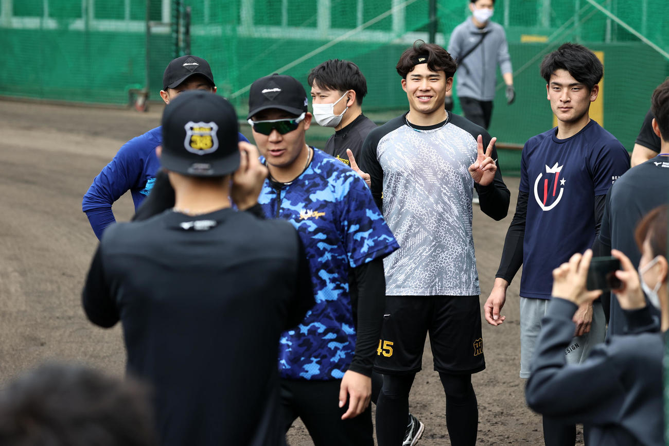 グラウンドで小幡カメラマン(手前）にVサインし記念撮影する左から島田、遠藤、高寺の真ん中に割って入ってきたのは…大山でした（撮影・加藤哉）
