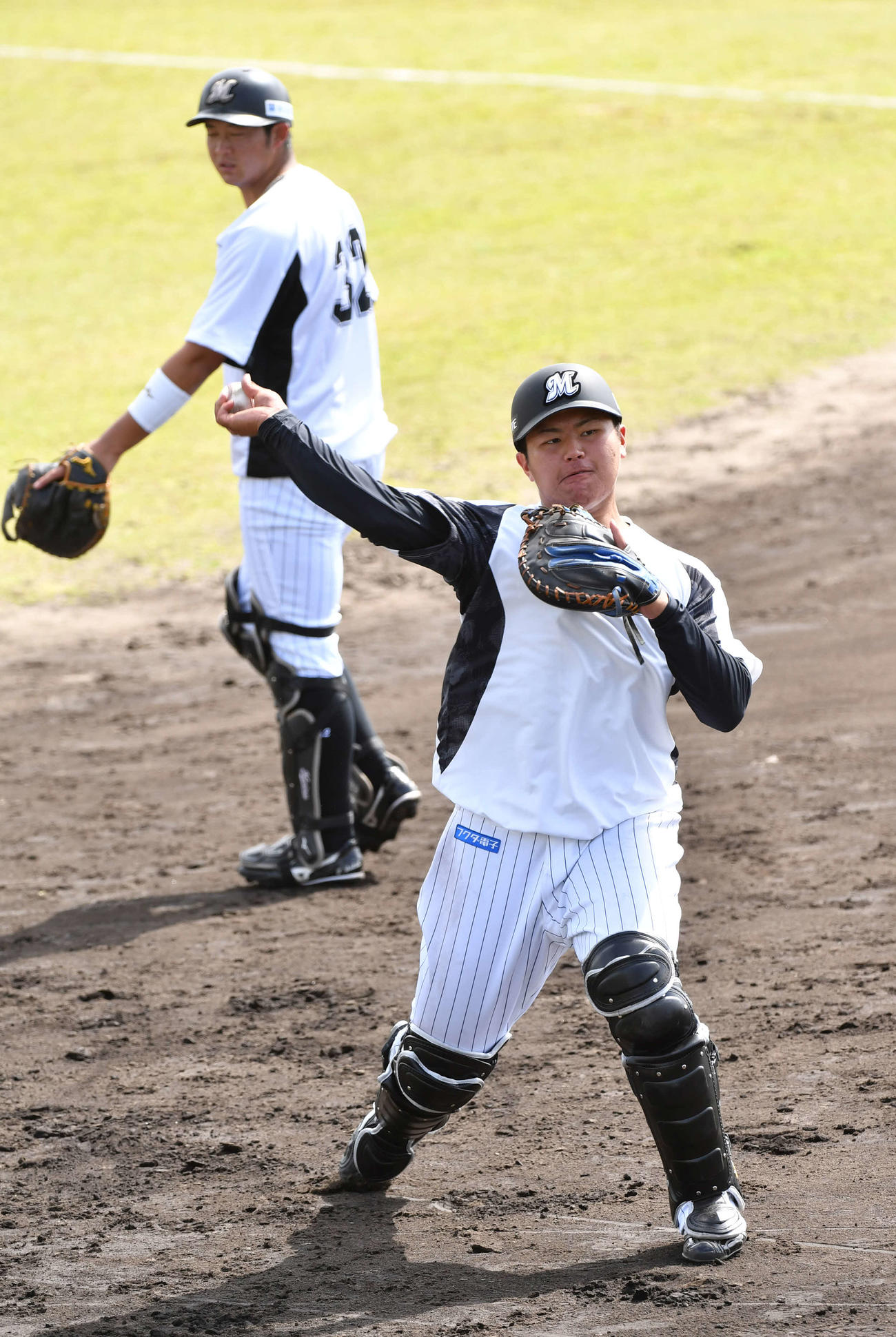 ロッテ石垣島キャンプ初日、送球練習するドラフト1位の松川捕手は98キロの堂々たる体格、後方は佐藤都捕手（撮影・柴田隆二）