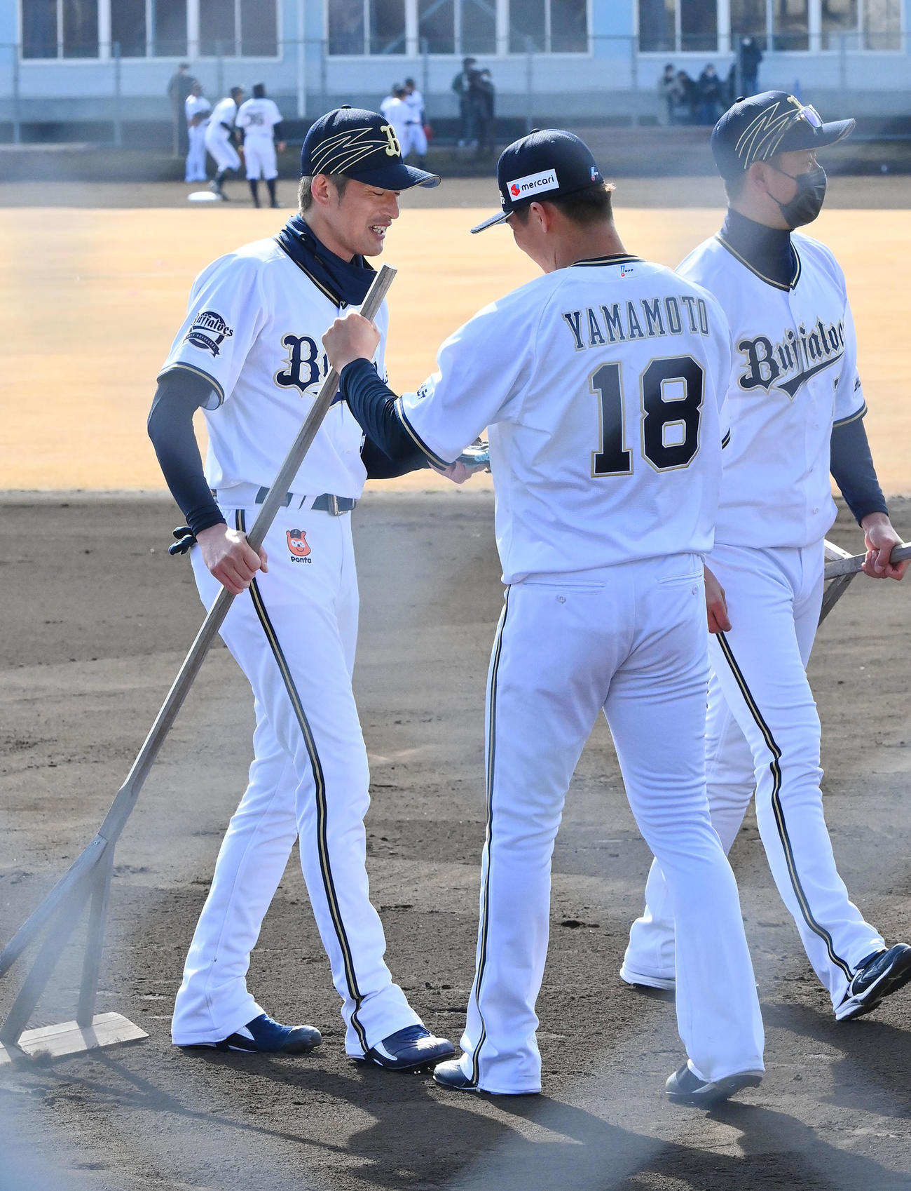 グラウンドの整備を終えオリックス能見（左）のトンボを受け取る山本（撮影・和賀正仁）