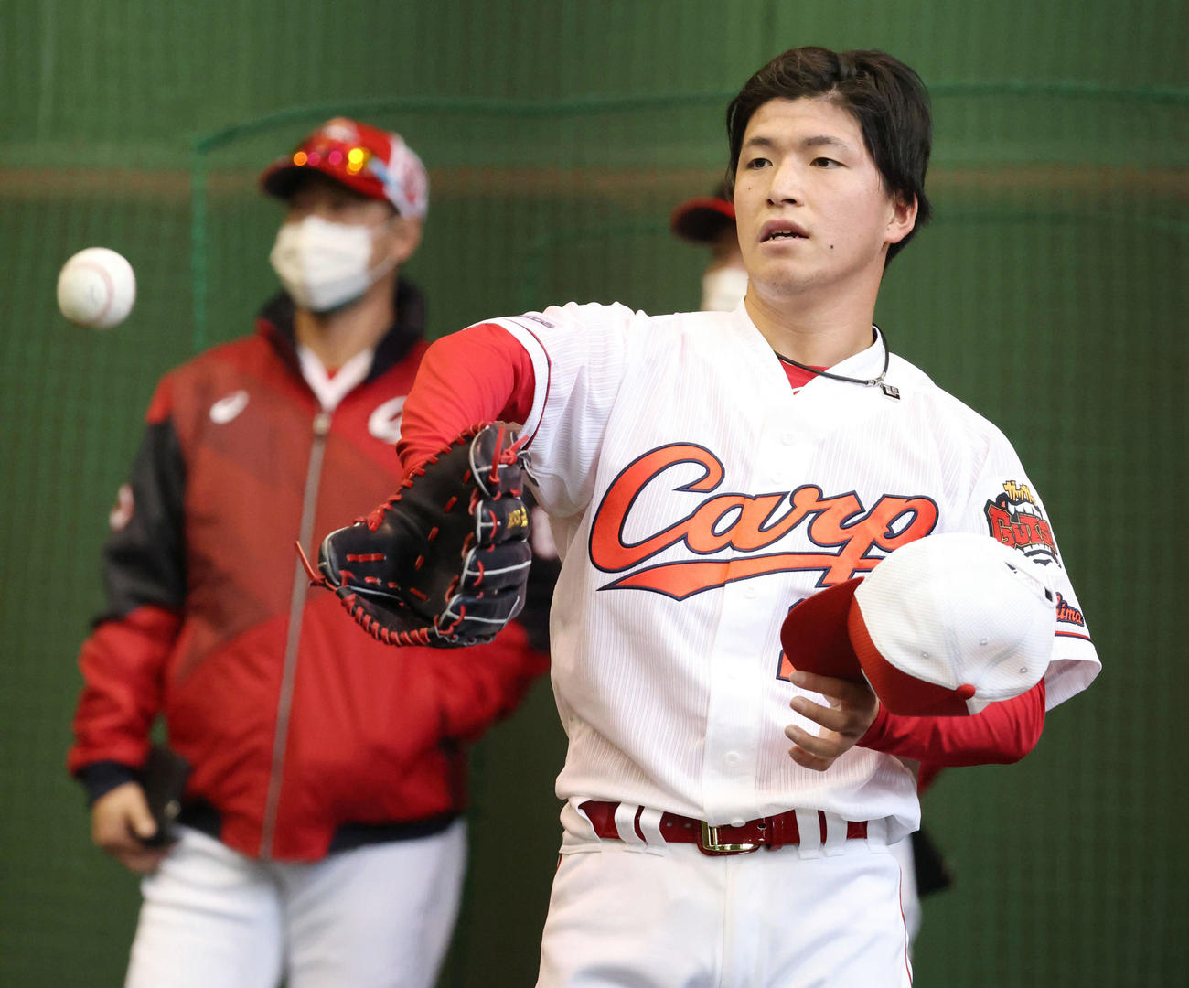 キャンプ初日、ブルペン入りし、投球した広島ドラフト1位の黒原。左は高橋投手コーチ（撮影・加藤孝規）