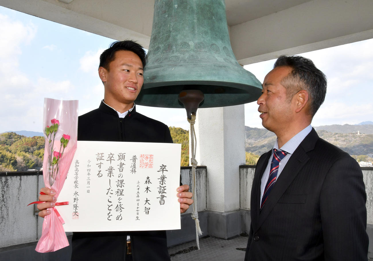 高知高校のシンボル「世界の鐘」の前で卒業証書を手にする阪神ドラフト1位森木。右は浜口監督（代表撮影）