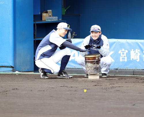 西武の春季キャンプ2日目、練習を待つ間、ベンチ前の炭火で温まる山田遙楓（左）と源田壮亮（撮影・浅見桂子）