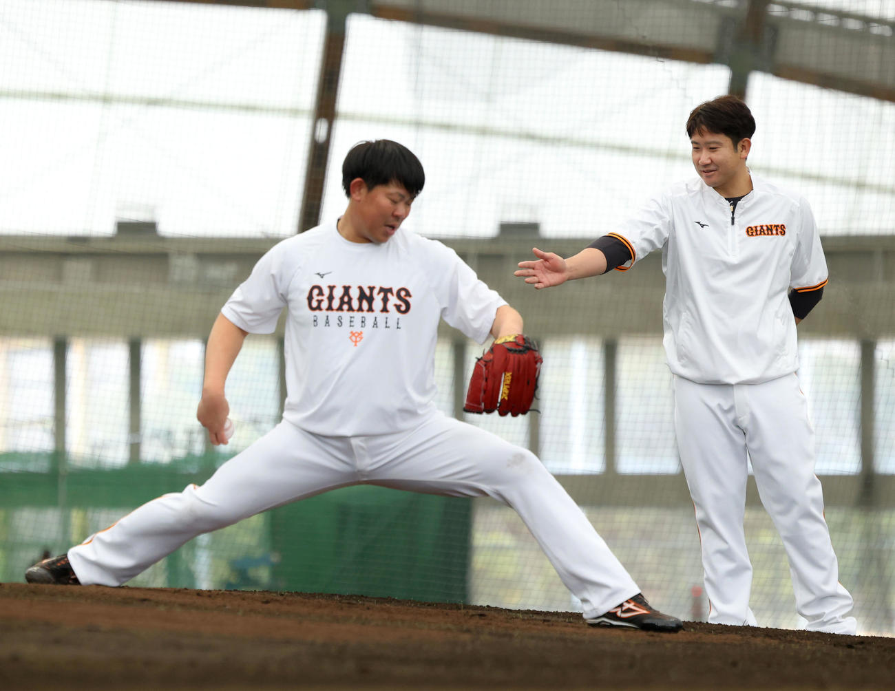 ブルペン投球する巨人山口（左）にアドバイスする菅野（撮影・河田真司）