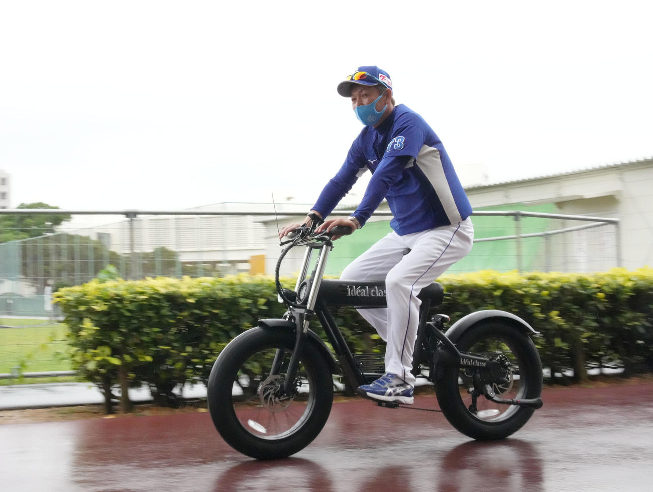 雨の降る中、自転車でメイン球場と屋内運動場を移動する中日立浪監督（撮影・森本幸一）