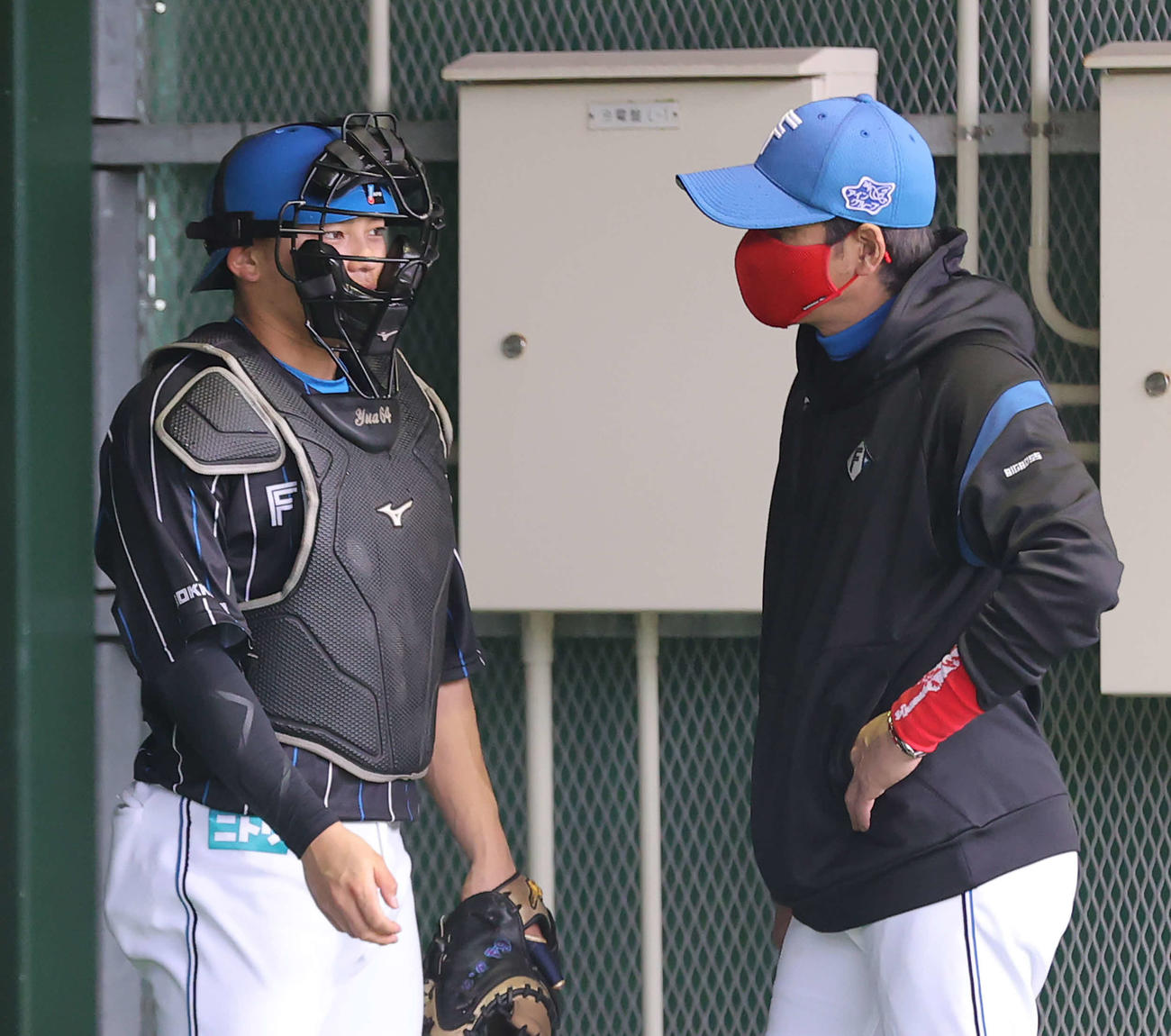 ブルペンで日本ハム長谷川威の球を受ける田宮（左）と言葉を交わす新庄監督（撮影・河野匠）