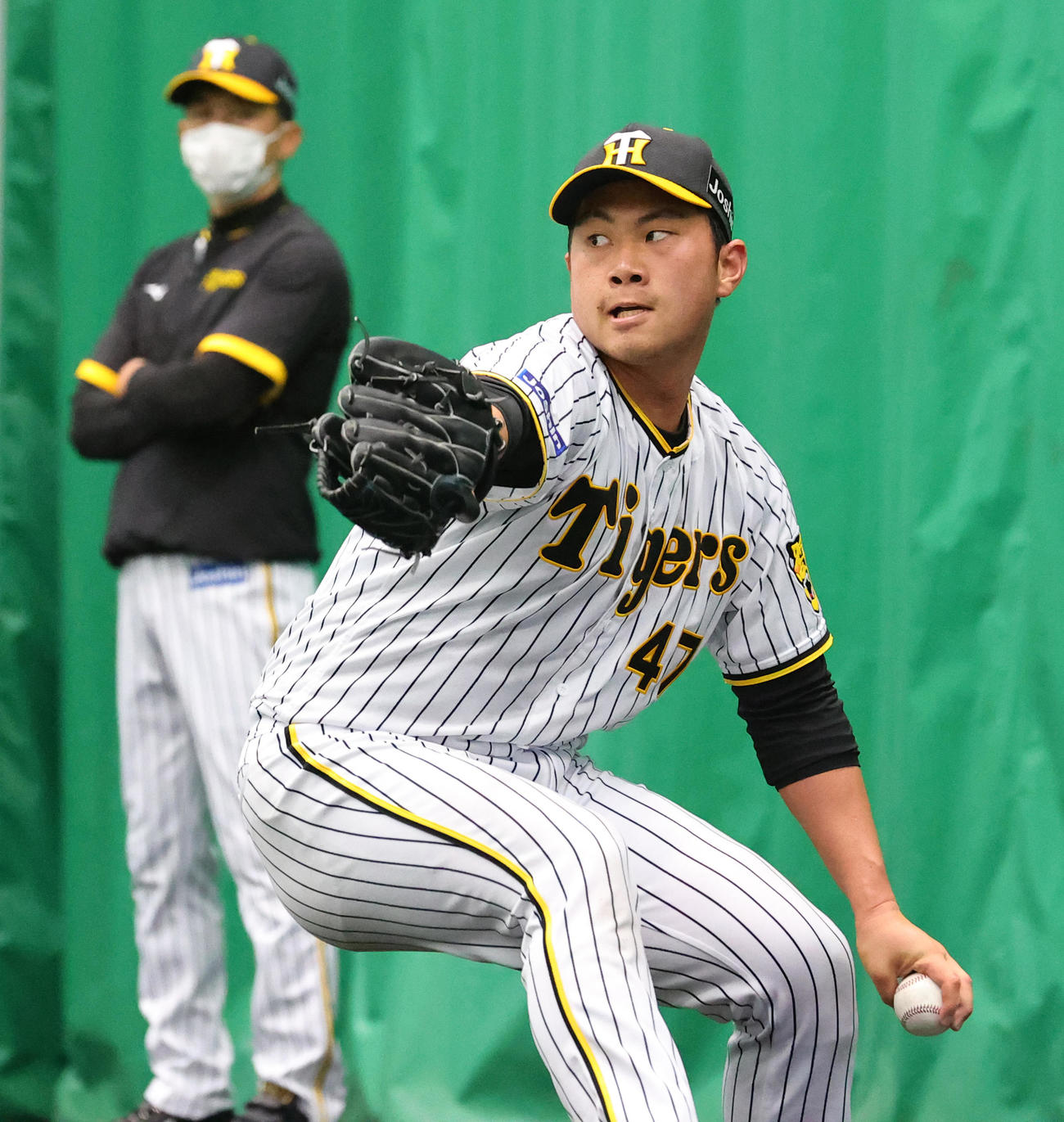 ブルペンで投球する桐敷。後方は矢野監督（撮影・上山淳一）