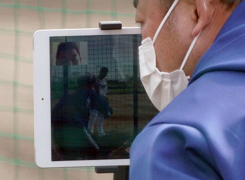 タブレットを使用し遠隔指導をする中村紀打撃コーチ（タブレット画面内左上）（撮影・森本幸一）