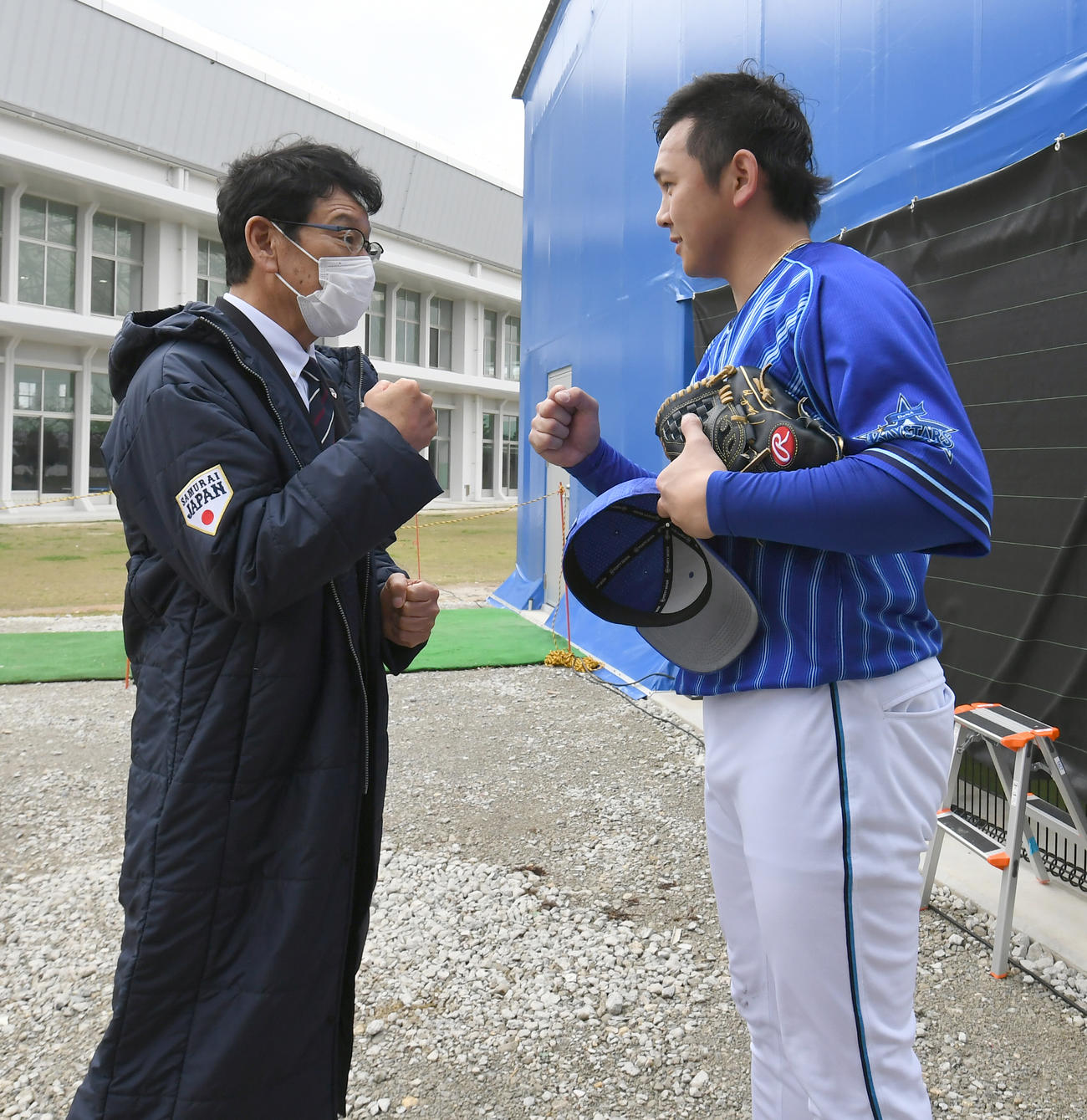 宜野湾キャンプを訪問した日本代表の栗山監督（左）は投球を終えあいさつに来たDeNA山崎とグータッチする（代表撮影）