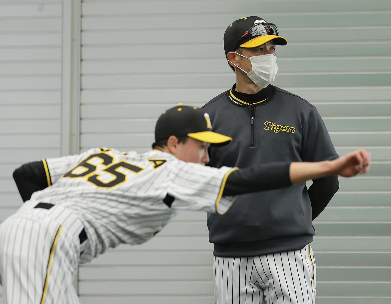 ブルペンで阪神湯浅（手前）の投球練習を見つめる矢野監督（撮影・前田充）