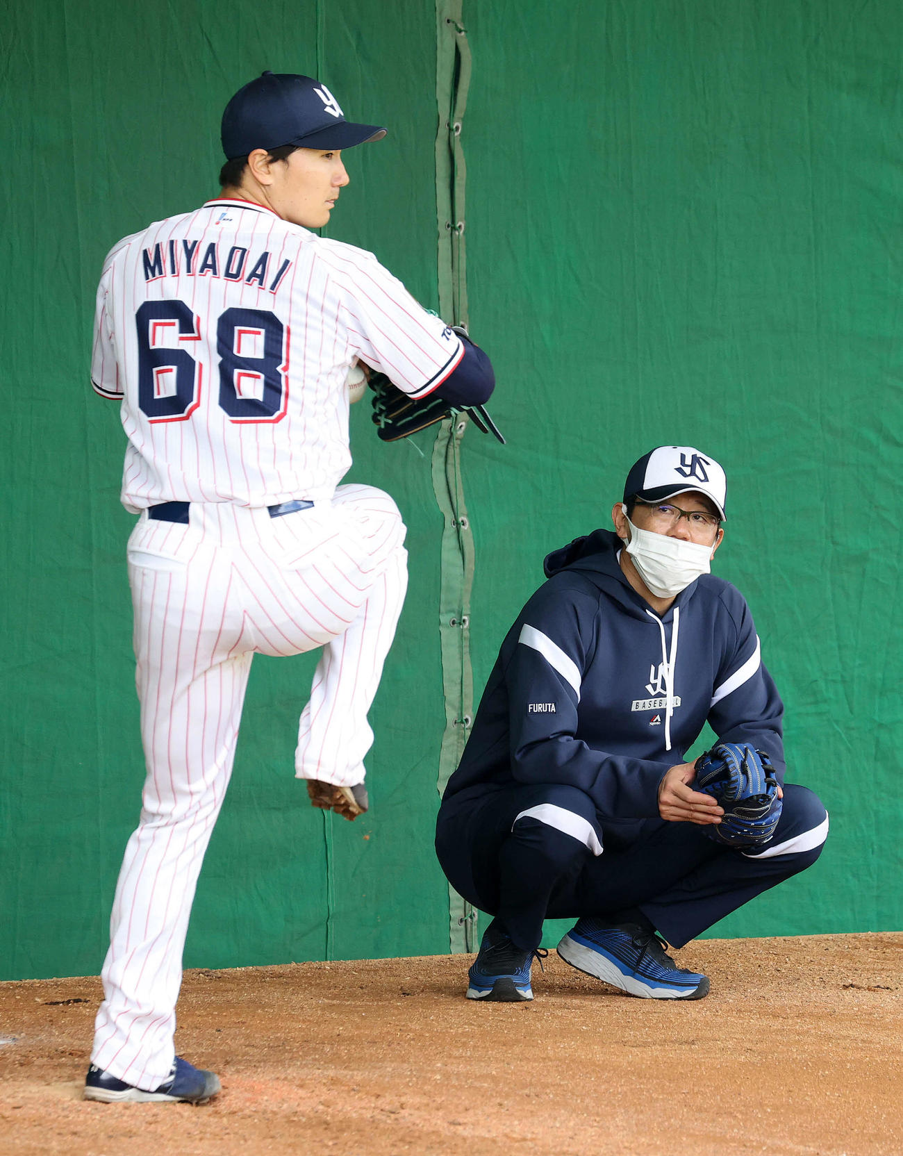ブルペンで宮台（左）の投球練習を見る古田臨時コーチ（撮影・鈴木正人）