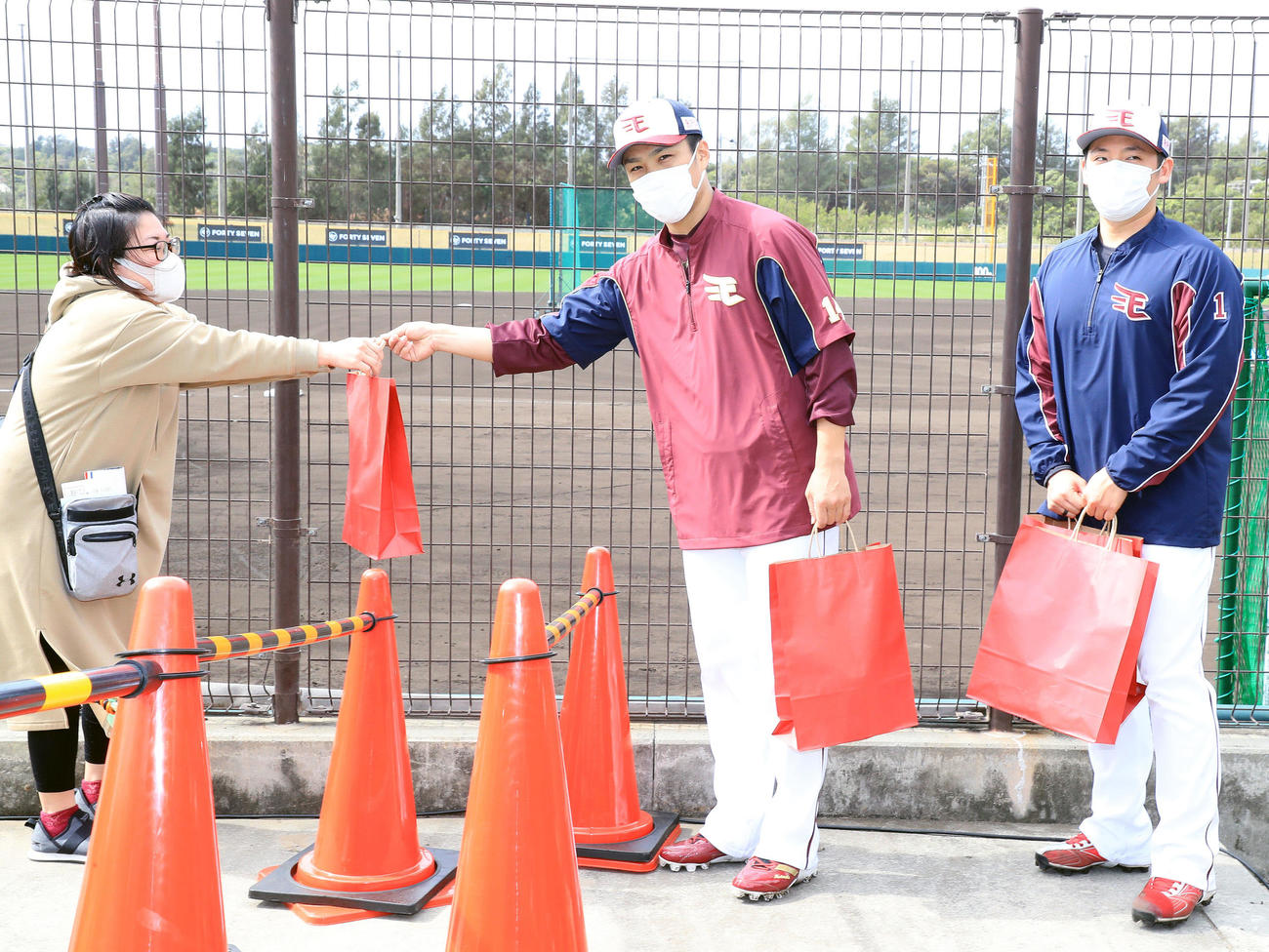 キャンプを見学するファンにサプライズでプレゼントを配る楽天則本昂（左）と松井裕