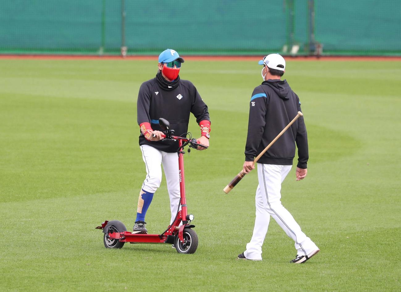 球場内を電動キックボードで移動し紺田コーチと話す日本ハム新庄監督（撮影・黒川智章）