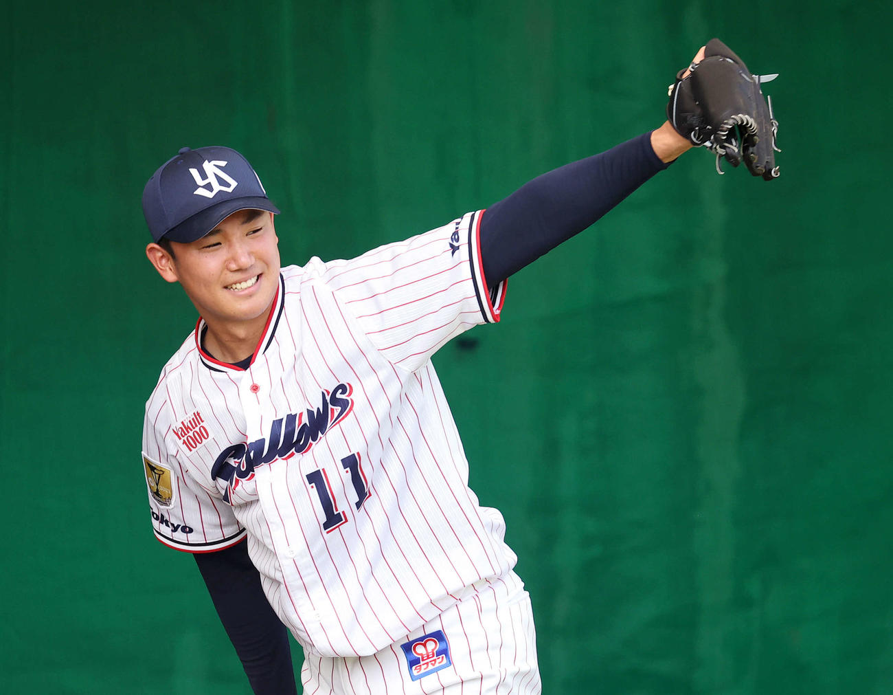 ブルペンで投球練習中、笑顔を見せるヤクルト奥川恭伸（撮影・鈴木正人）