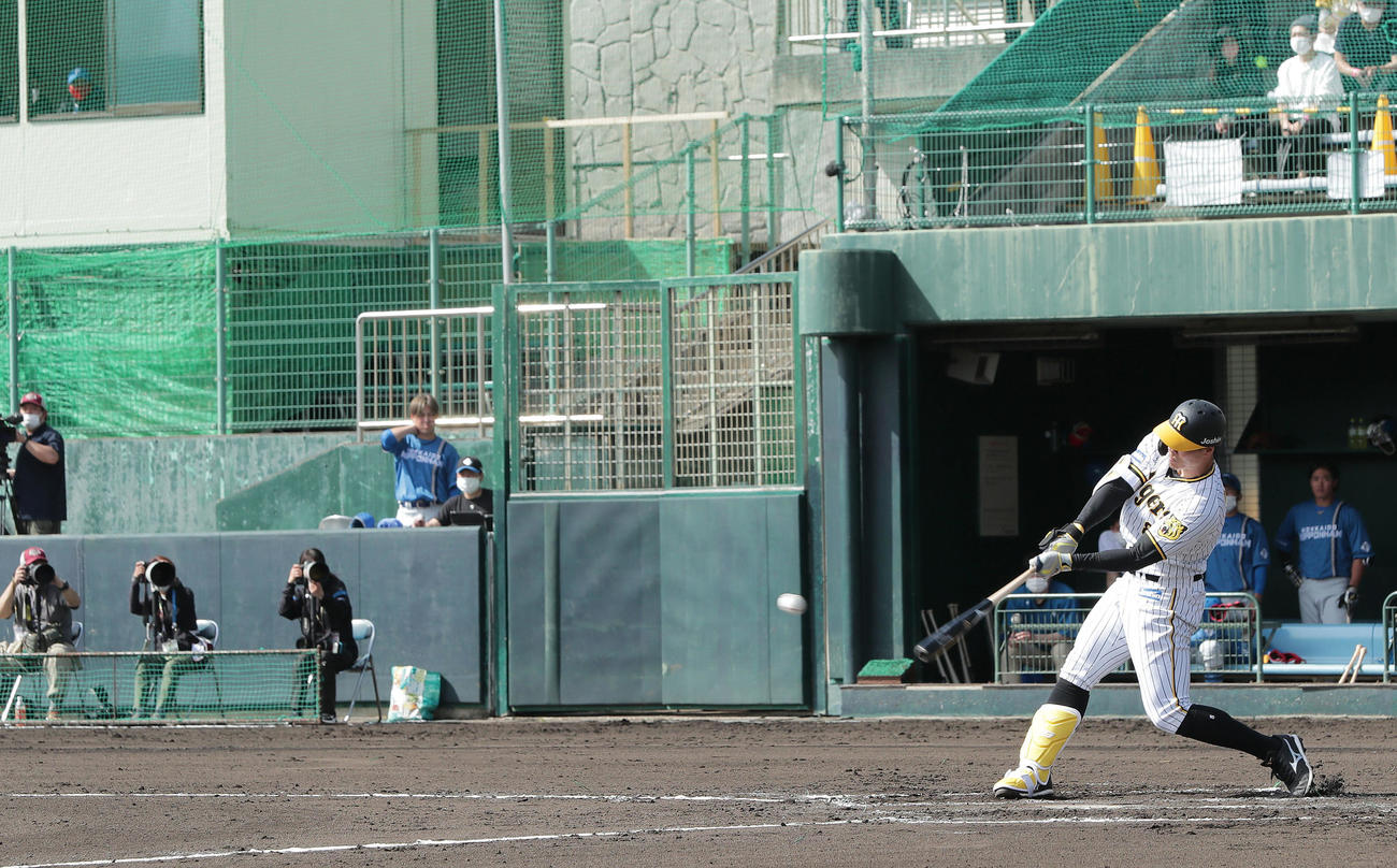 阪神対日本ハム　1回裏阪神2死三塁、左前適時打を放つ佐藤輝。左上の窓から見つめるのは日本ハム新庄監督（撮影・前田充）