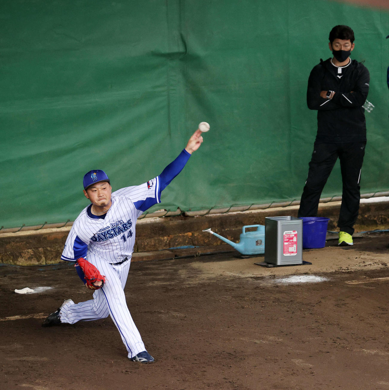 DeNA三浦監督（右）の前で投球練習する石田（撮影・鈴木正人）