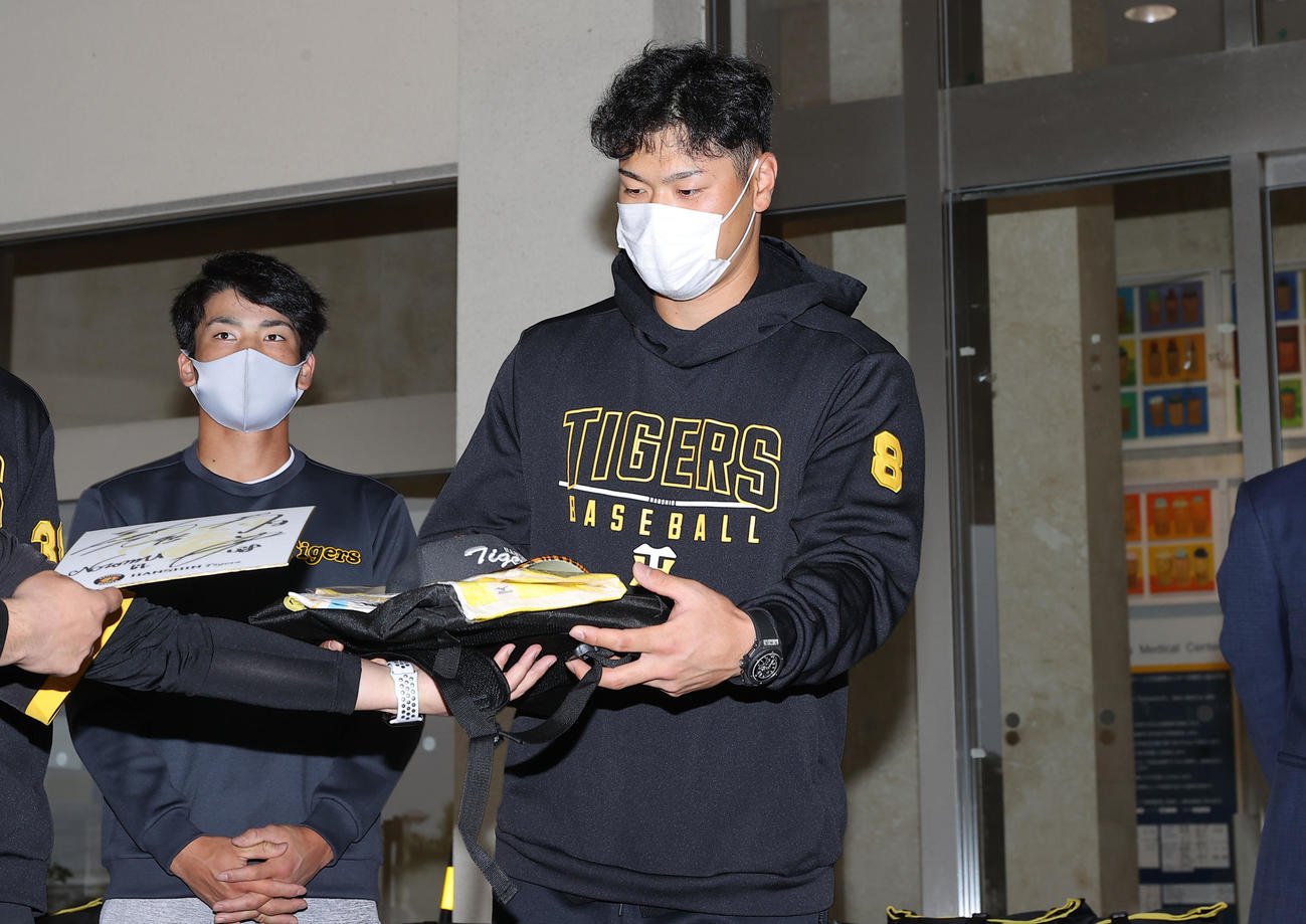 タイガースグッズを病院関係者に手渡す阪神佐藤輝明。左は高寺（代表撮影）