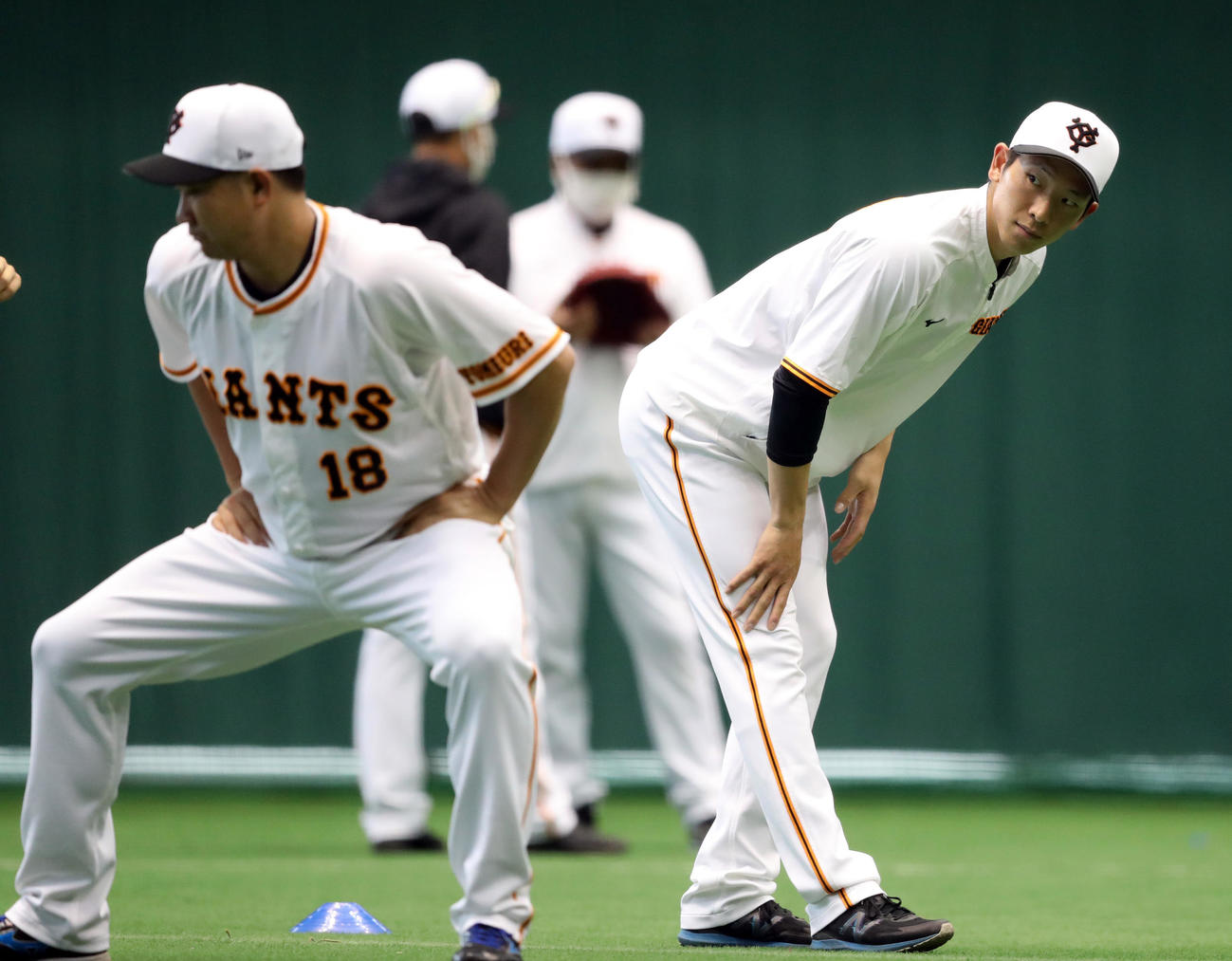 投手陣練習でのウオーミングアップで菅野（左）を見つめる戸郷（撮影・狩俣裕三）