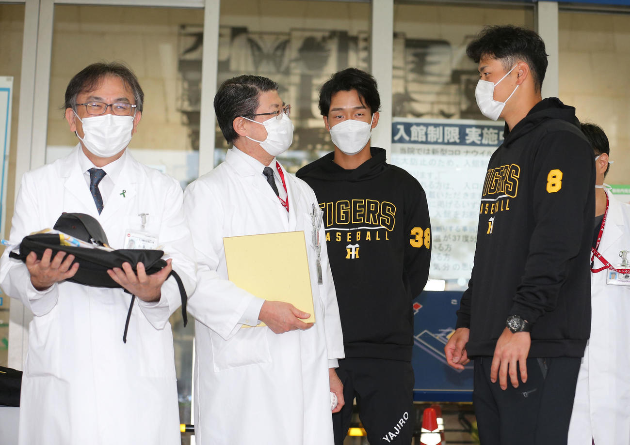こども医療センターに訪問し、佐藤輝（右）と小幡（右から2人目）は、タイガースグッズを渡し、病院関係者と話す（代表撮影）