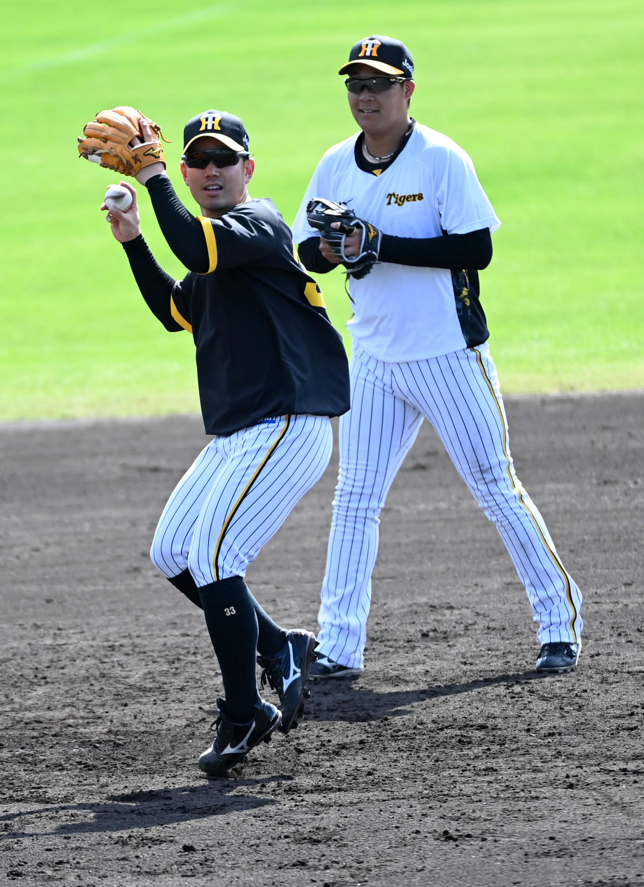 三塁でノックを受ける糸原（左）。右は大山（撮影・前岡正明）