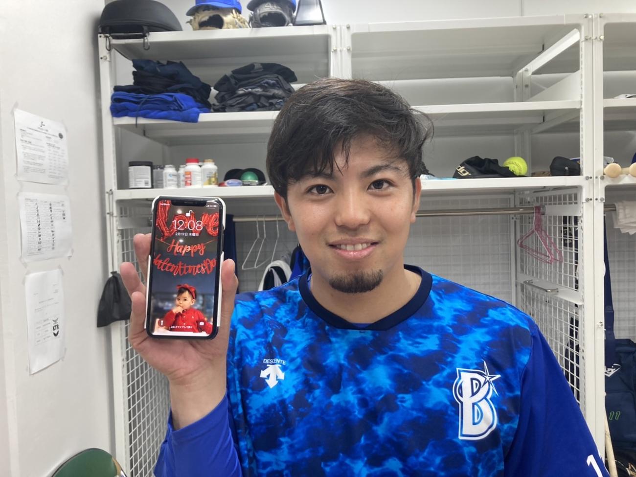 長女が待ち受け画面のスマートフォンを手に笑顔のDeNA東（球団提供）