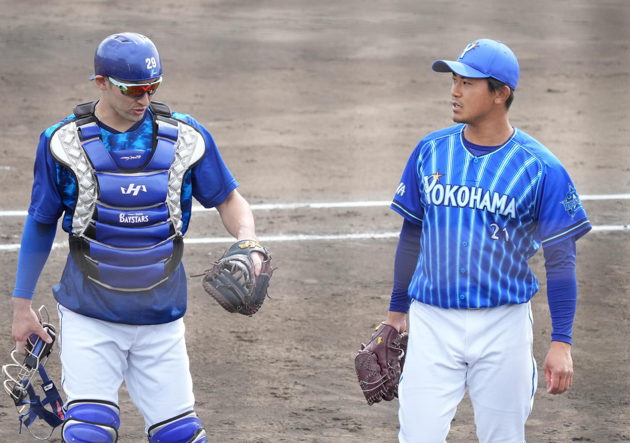 7日、フリー打撃登板を終え伊藤光（左）に投球内容を確認するDeNA今永