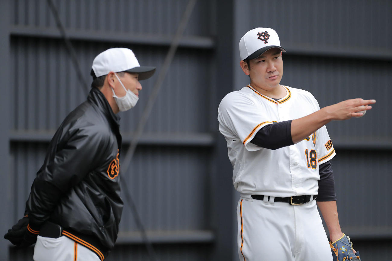ブルペンで桑田投手チーフコーチ（左）と言葉を交わす巨人菅野（2022年2月12日撮影）