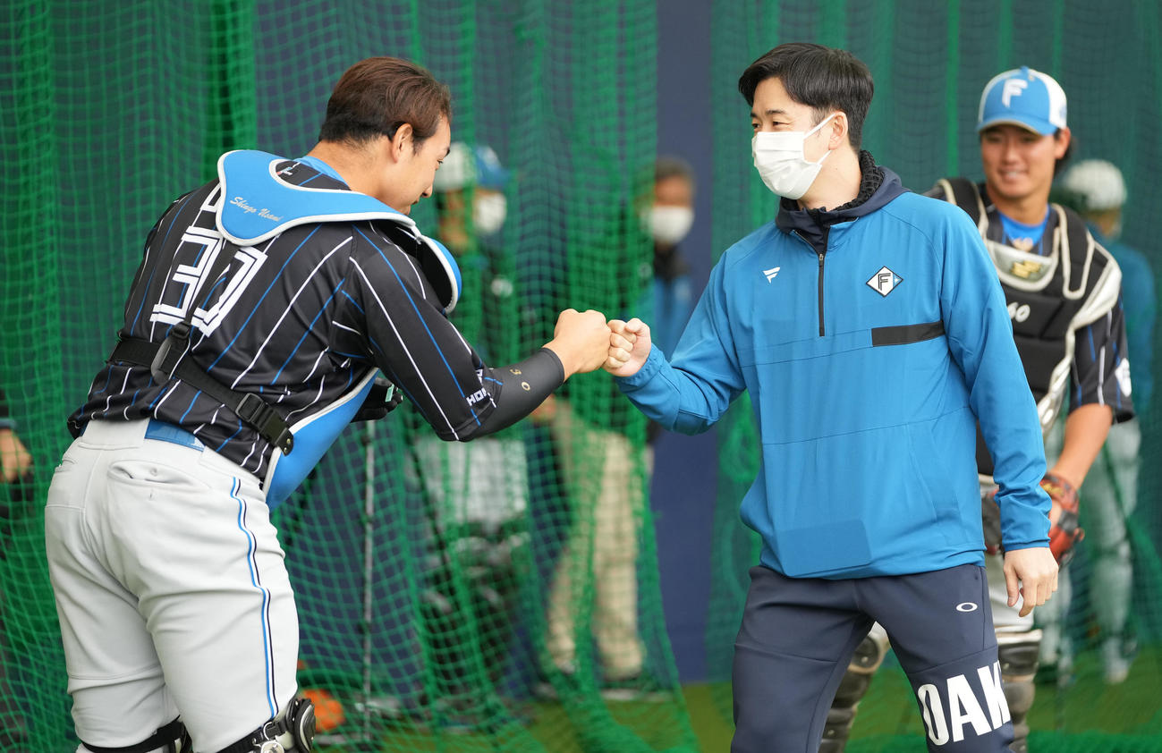 ブルペンで日本ハム宇佐見（左）とグータッチする斎藤佑樹氏（撮影・鈴木みどり）