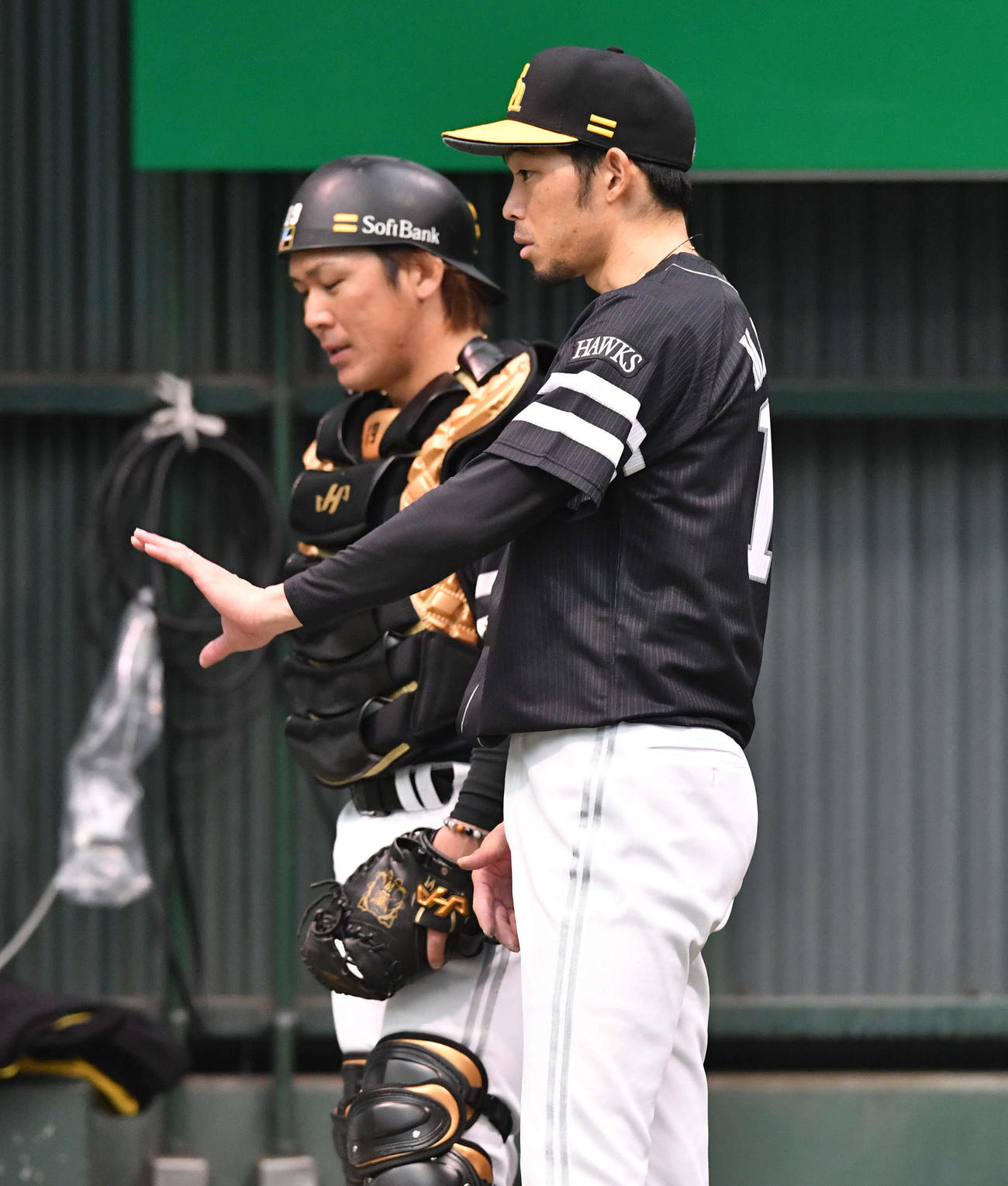 ブルペンでの投球を終え、甲斐（左）と話し合う又吉（撮影・岩下翔太）