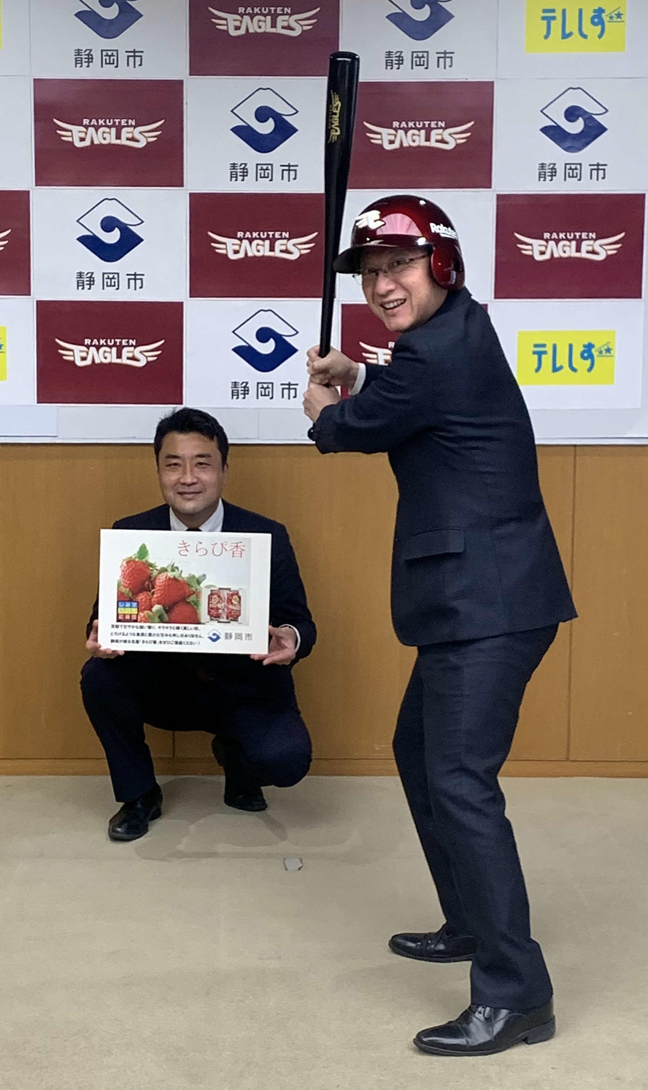 楽天から贈られた記念品のバットとヘルメットを装着し、笑顔を見せる田辺市長（右）。左は楽天松野野球振興部長