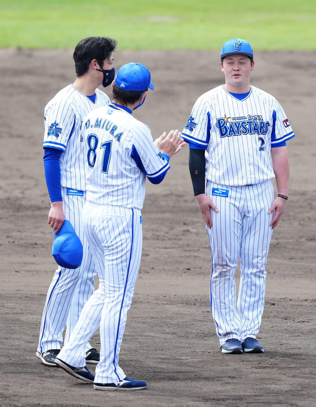 春季キャンプの手締めで声出しを行い、DeNA三浦監督（中央）から拍手を受ける牧。左は小園（撮影・江口和貴）