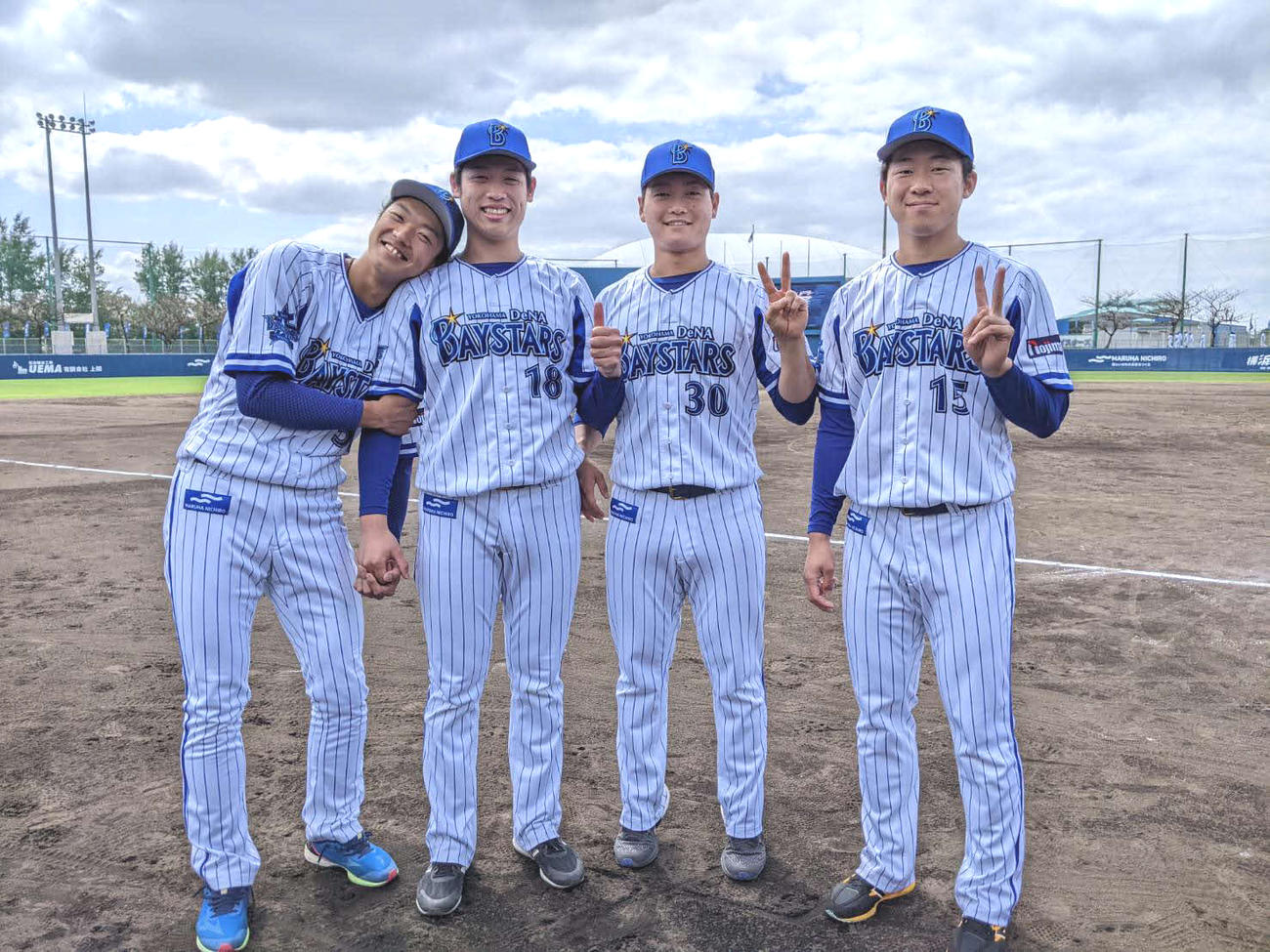 DeNA小園健太（左から2人目）の肩に頭を乗せ、満面の笑みでポーズを決めるDeNA梶原（左端）と三浦、徳山のルーキー4選手（球団提供）