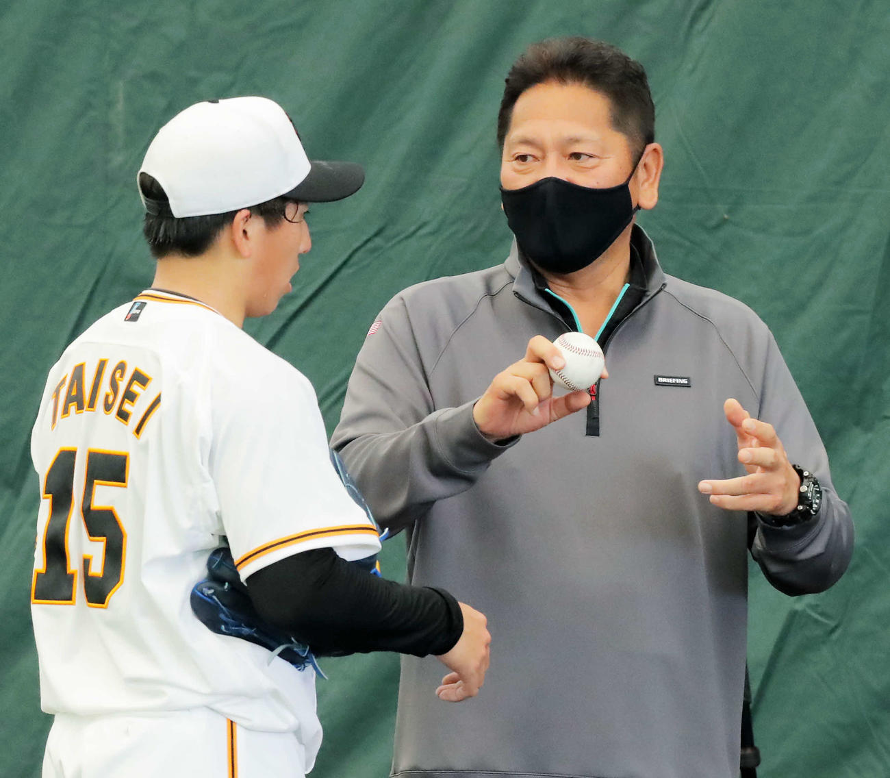 ブルペンで大勢（左）に握りのレクチャーをする佐々木氏（撮影・河田真司）