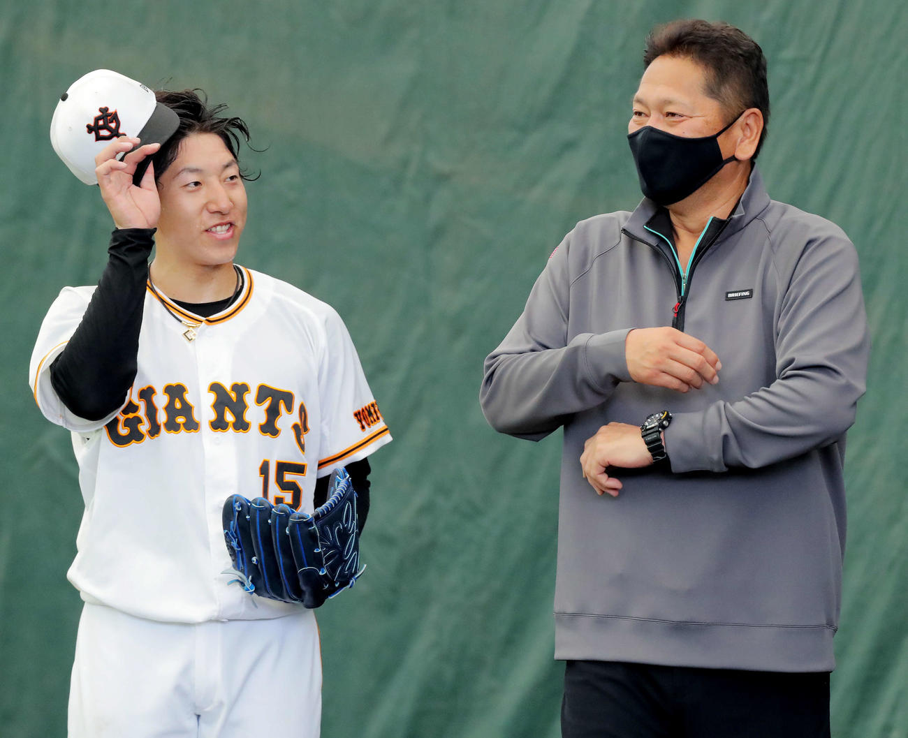 ブルペンで佐々木氏（右）からアドバイスを受け、笑顔を見せる大勢（撮影・河田真司）