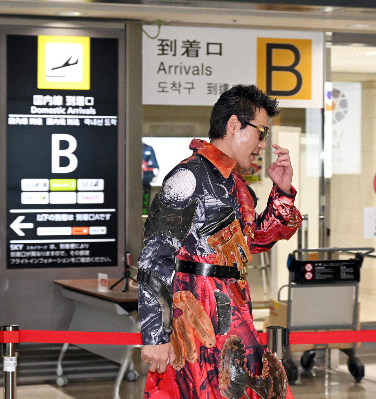 グローブやボール柄のコート姿で那覇空港に到着した日本ハム新庄監督（2022年1月30日撮影）