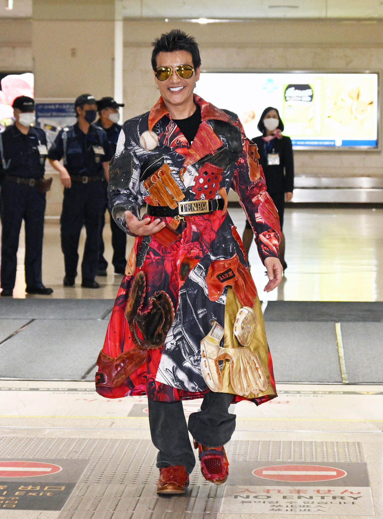 グローブ柄のコート姿で那覇空港に到着した日本ハム新庄監督はボールを放り笑顔（2022年1月30日　撮影）