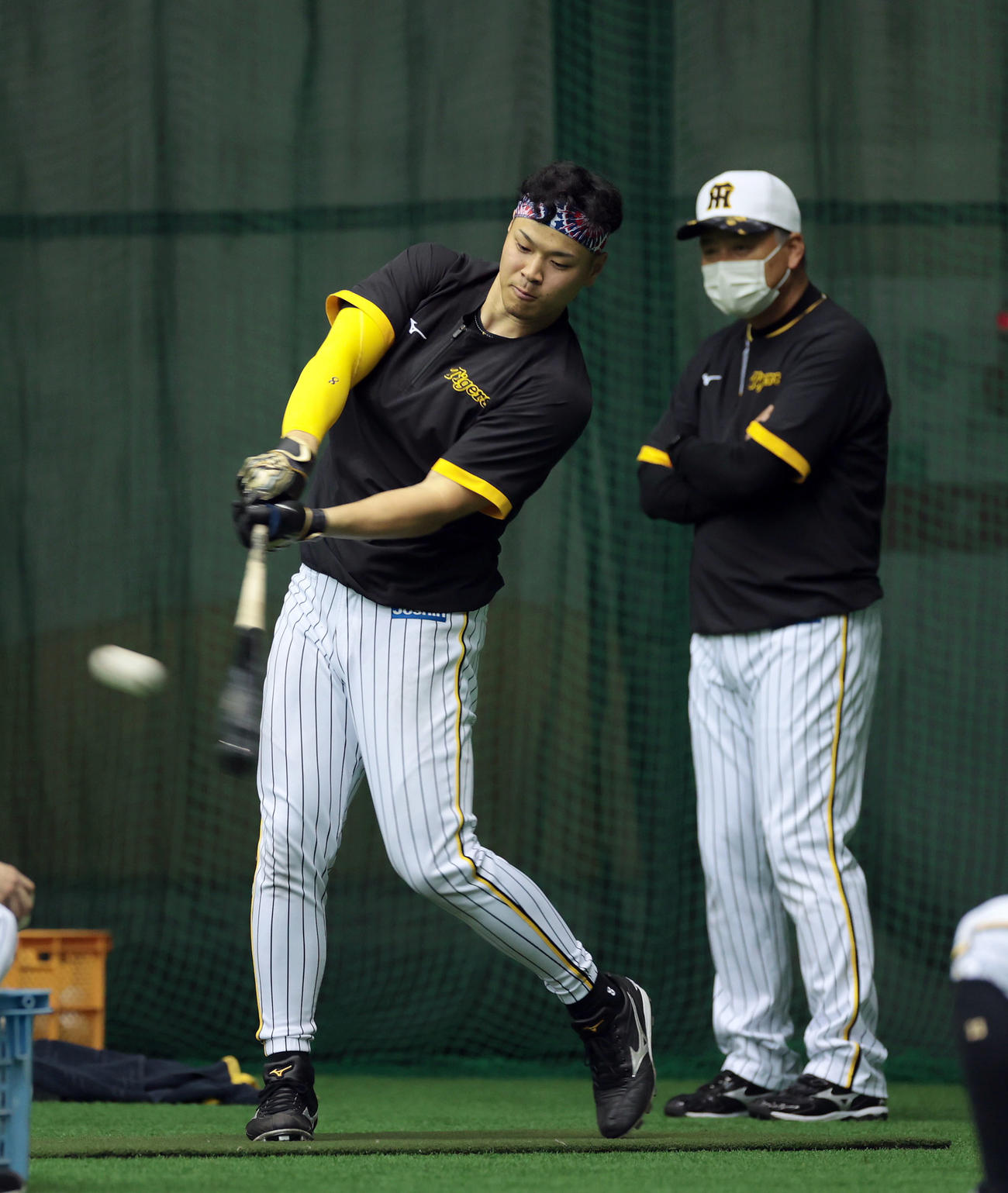 阪神藤井康雄コーチ（右）が見守る中、ロングティー打撃を行う佐藤輝（2022年2月3日撮影）